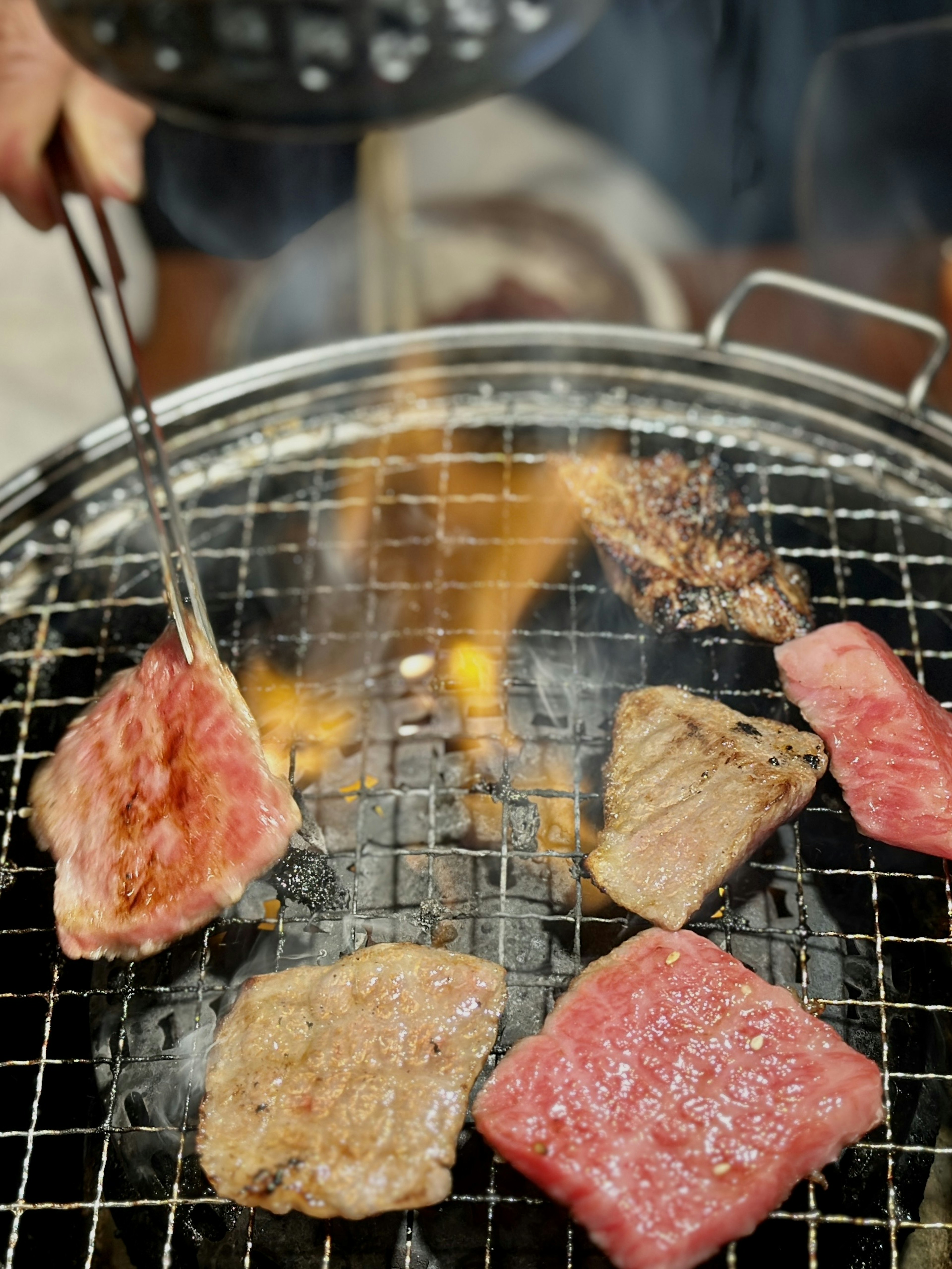 Slices of meat grilling on a barbecue with flames