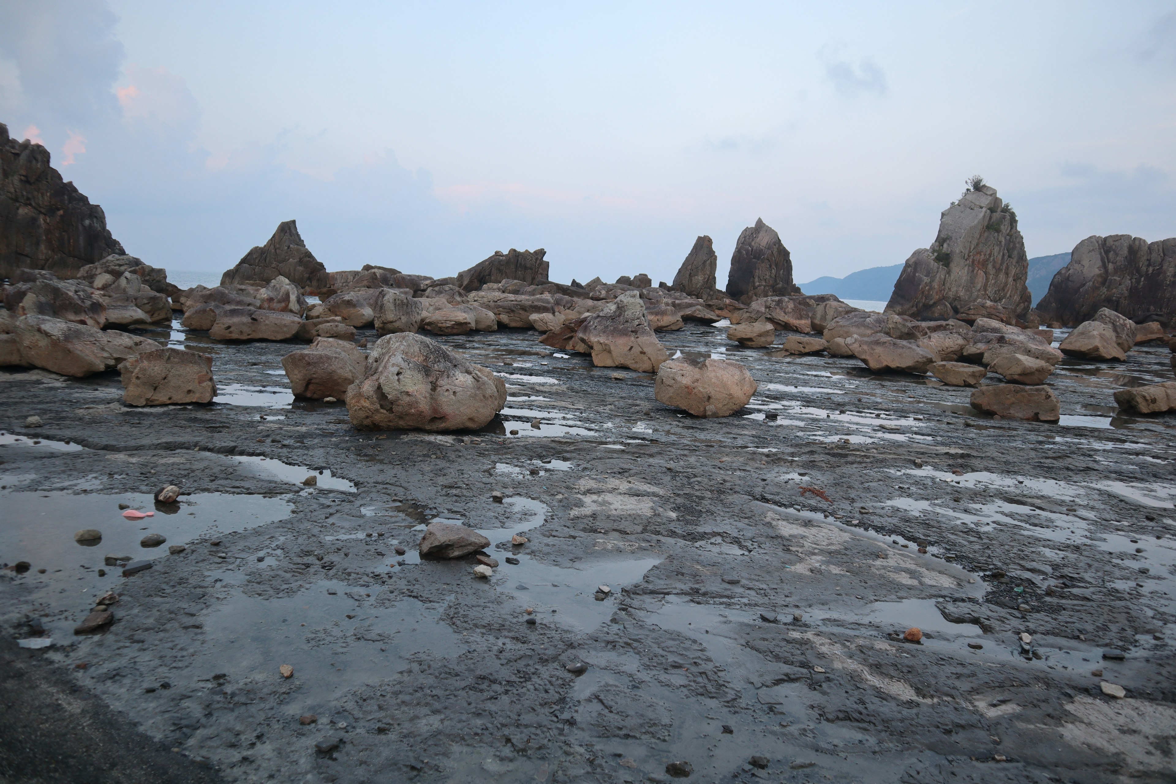 Paisaje costero con rocas dispersas reflejando el cielo crepuscular