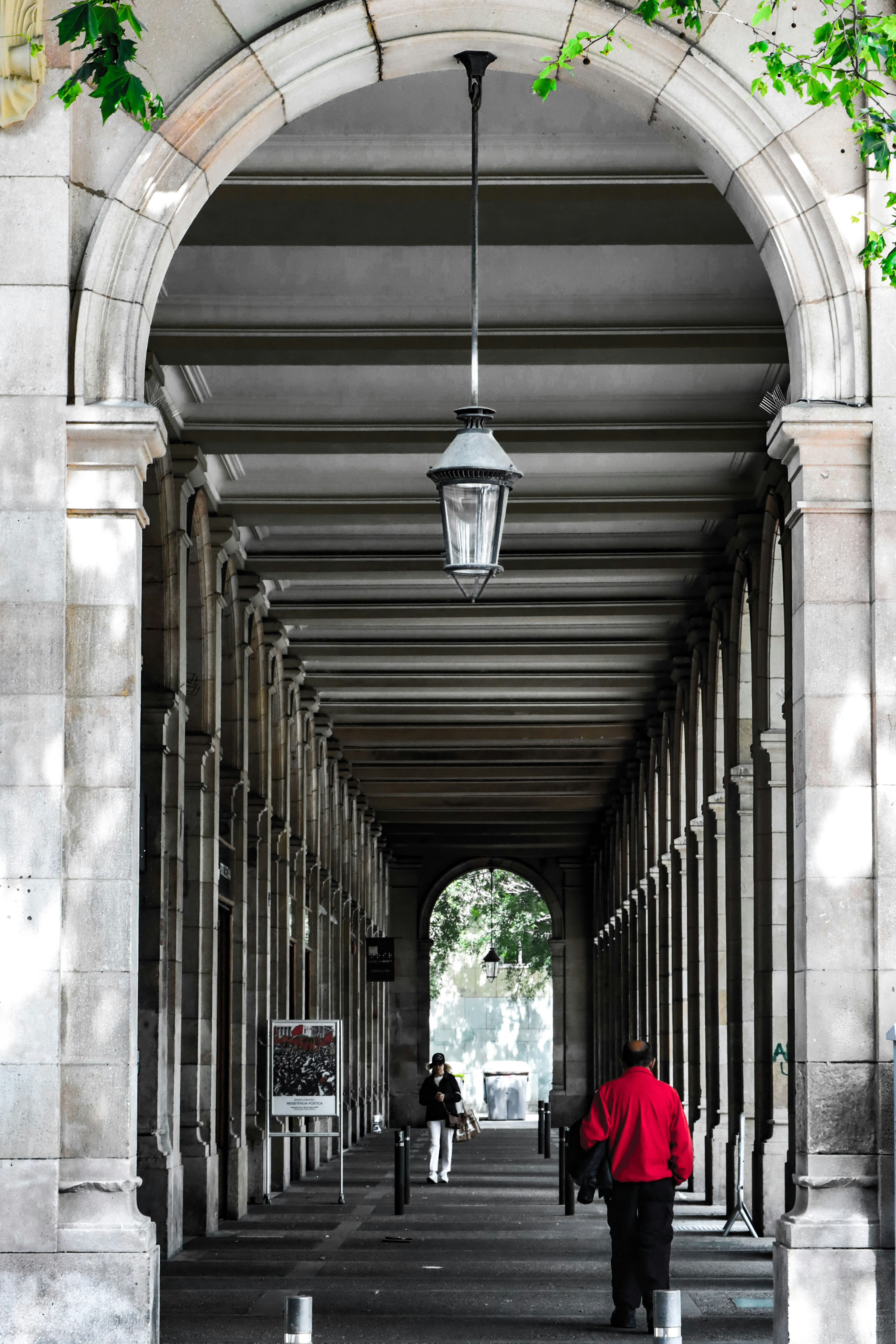 Couloir en arcade avec une personne en manteau rouge et une lampe suspendue