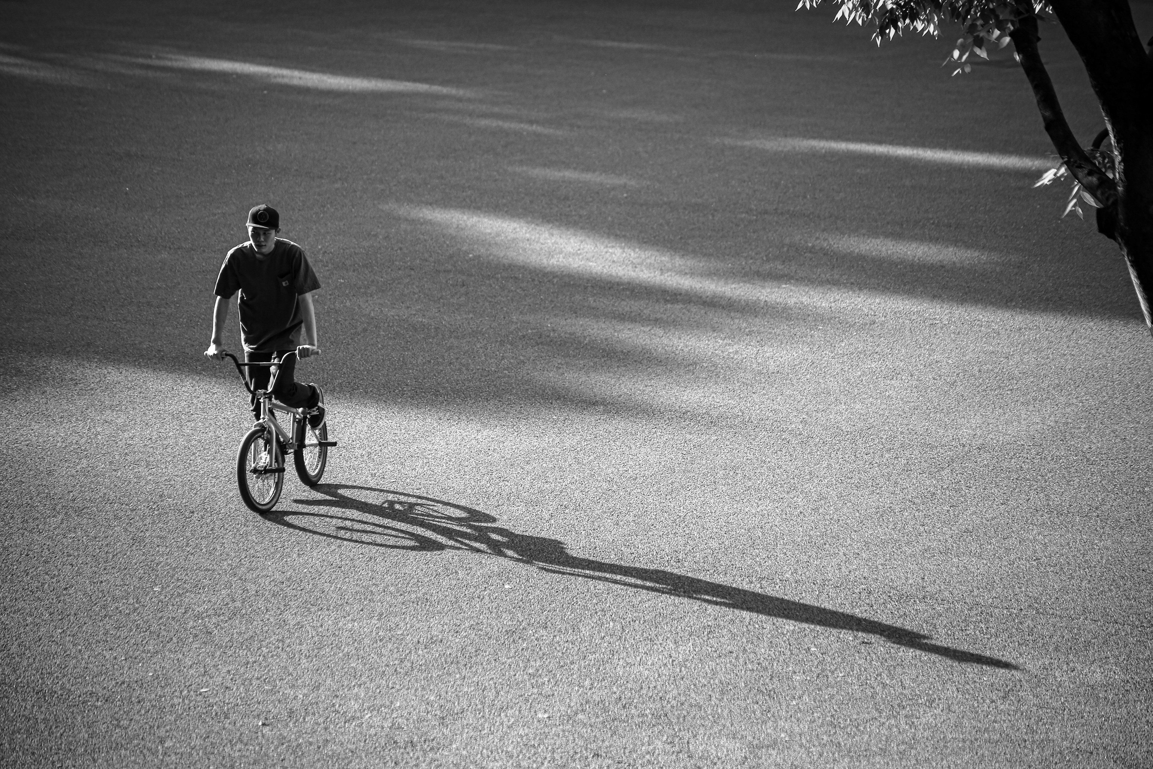 Foto in bianco e nero di un uomo in bicicletta con un'ombra lunga