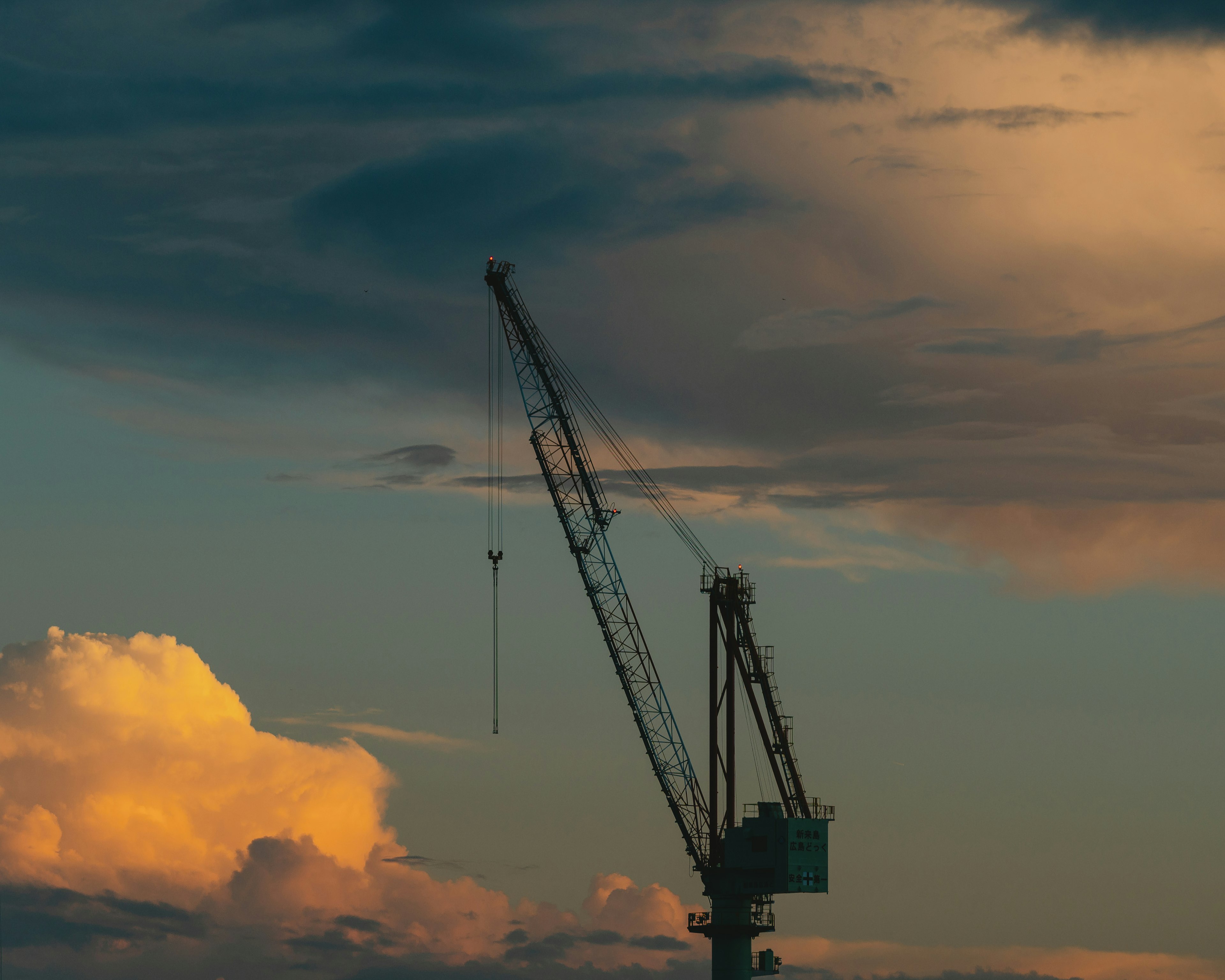 Silhouette of a crane against a colorful sunset sky with clouds