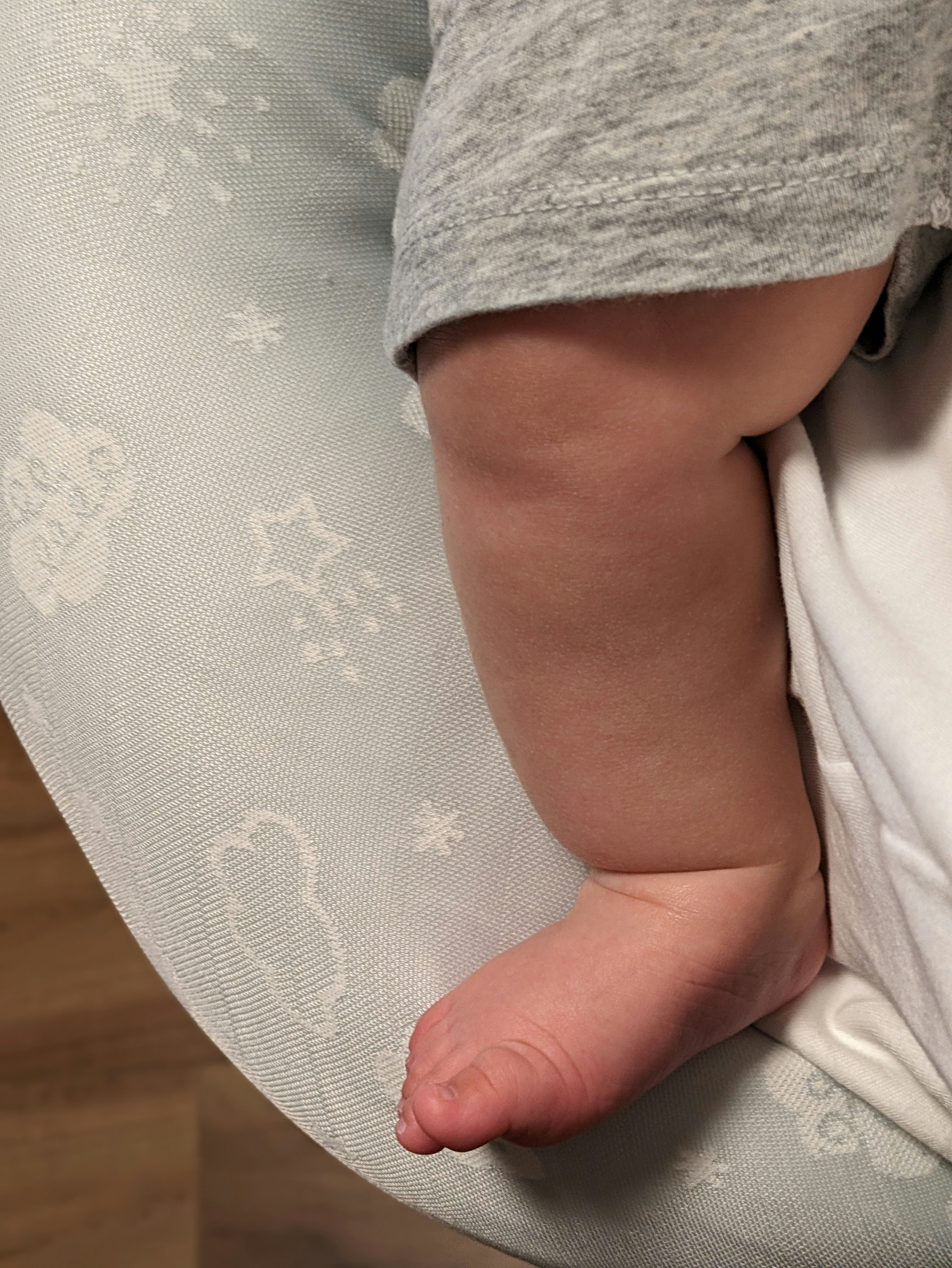 Baby's arm and foot resting on a soft cushion