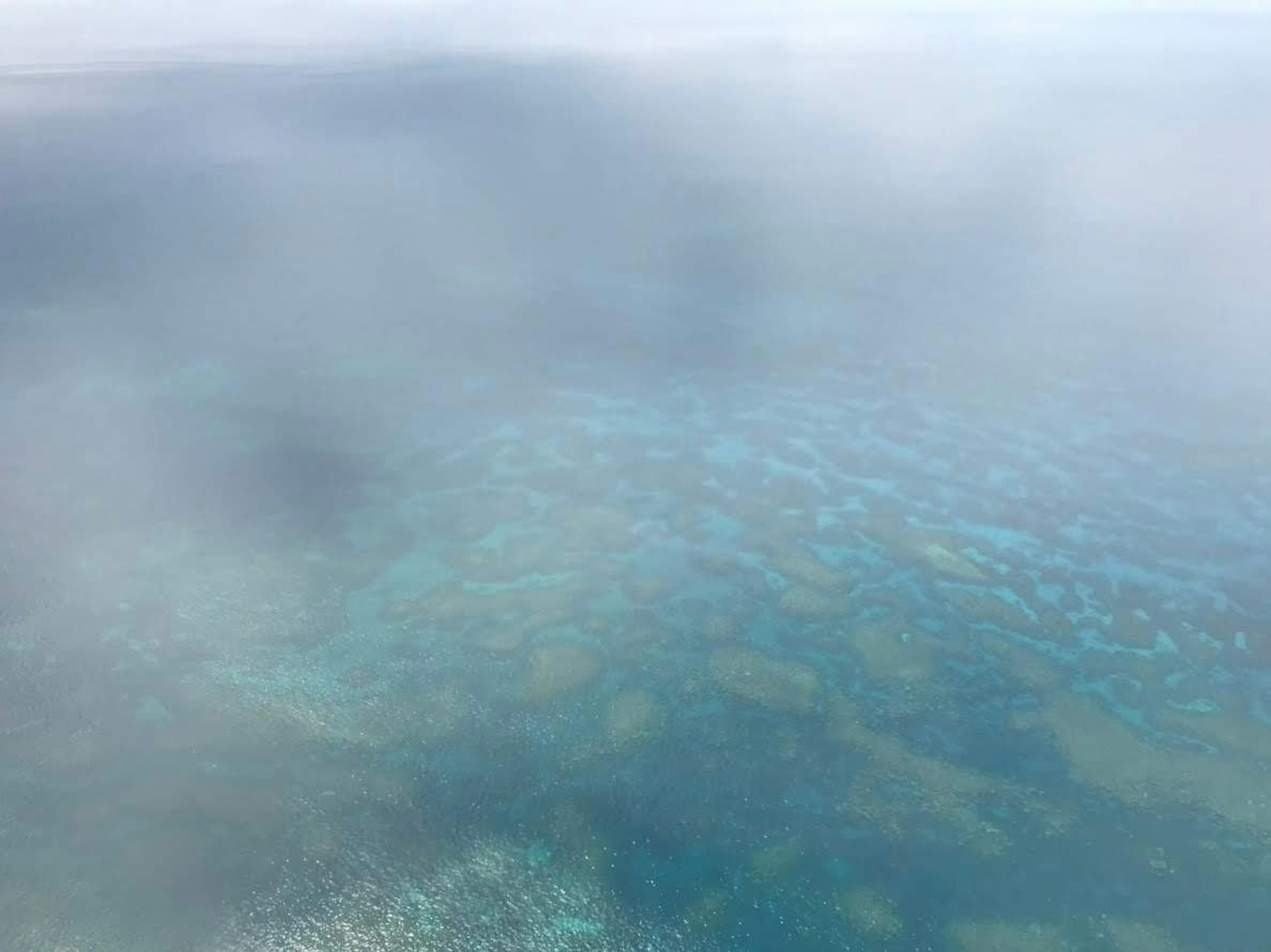 Vista aérea de arrecifes de coral parcialmente cubiertos por la niebla