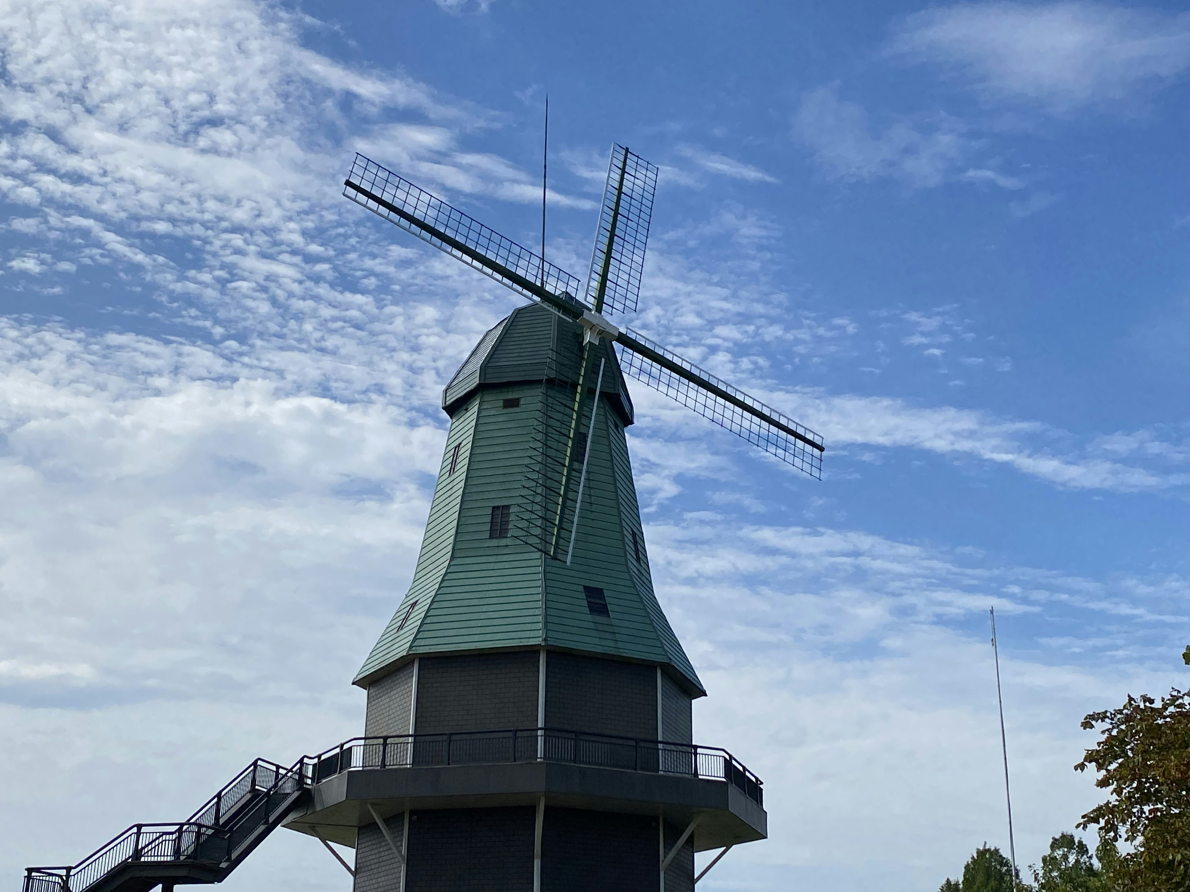 Vue latérale d'un moulin à vent avec un toit vert sous un ciel bleu