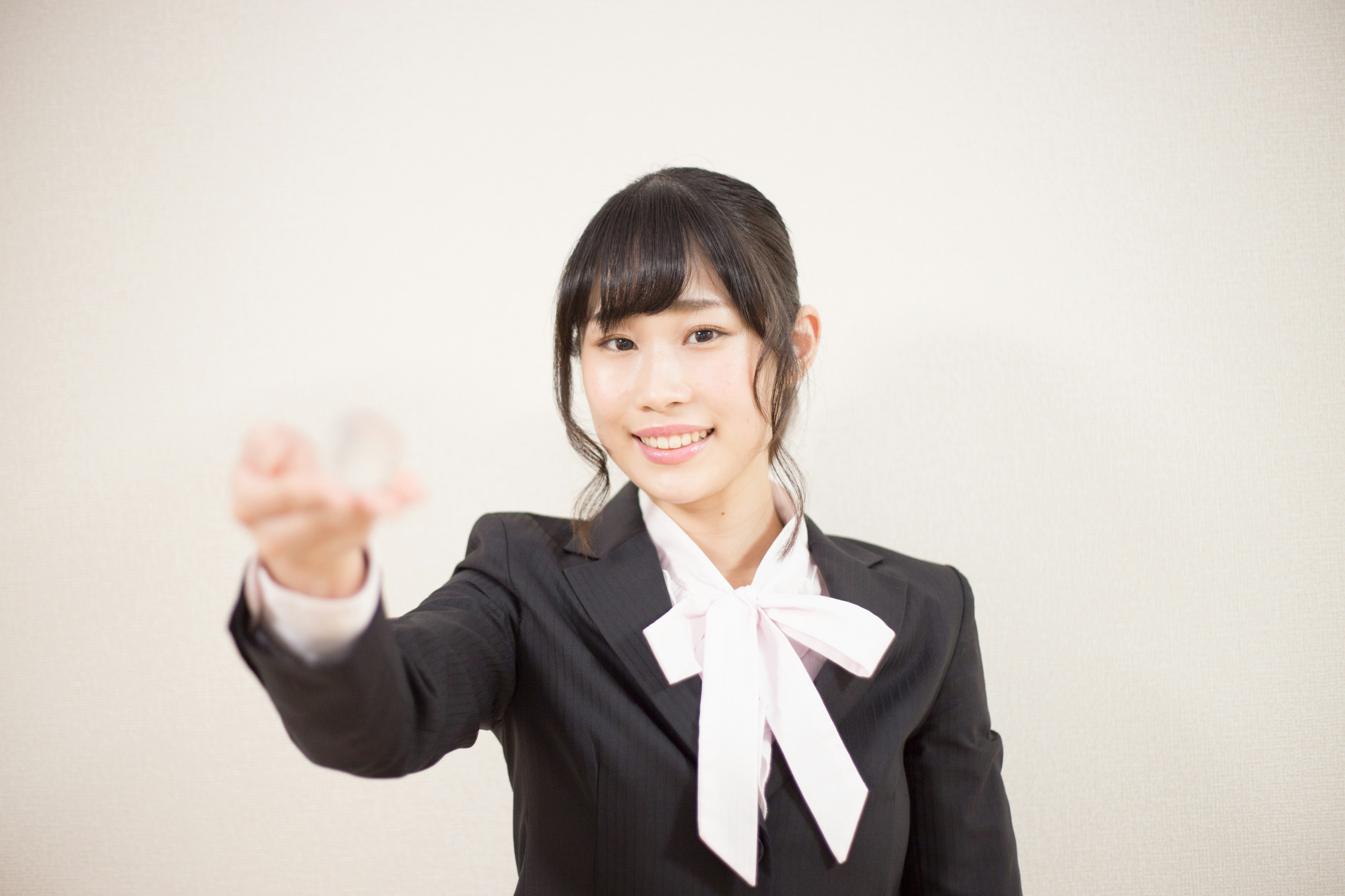 A woman in a black suit and white bow tie smiling and extending her hand