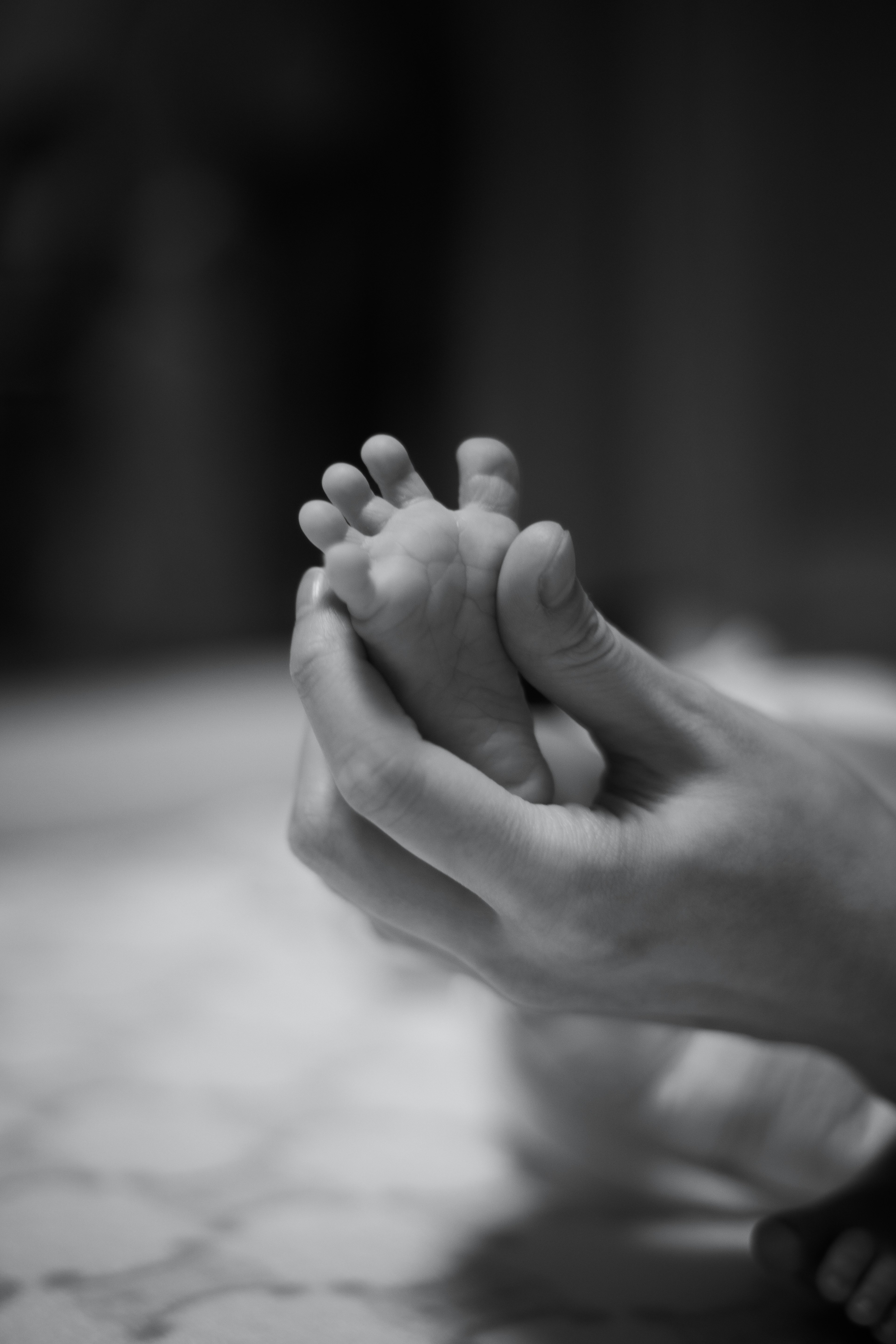 Close-up of hands gently holding a baby's foot