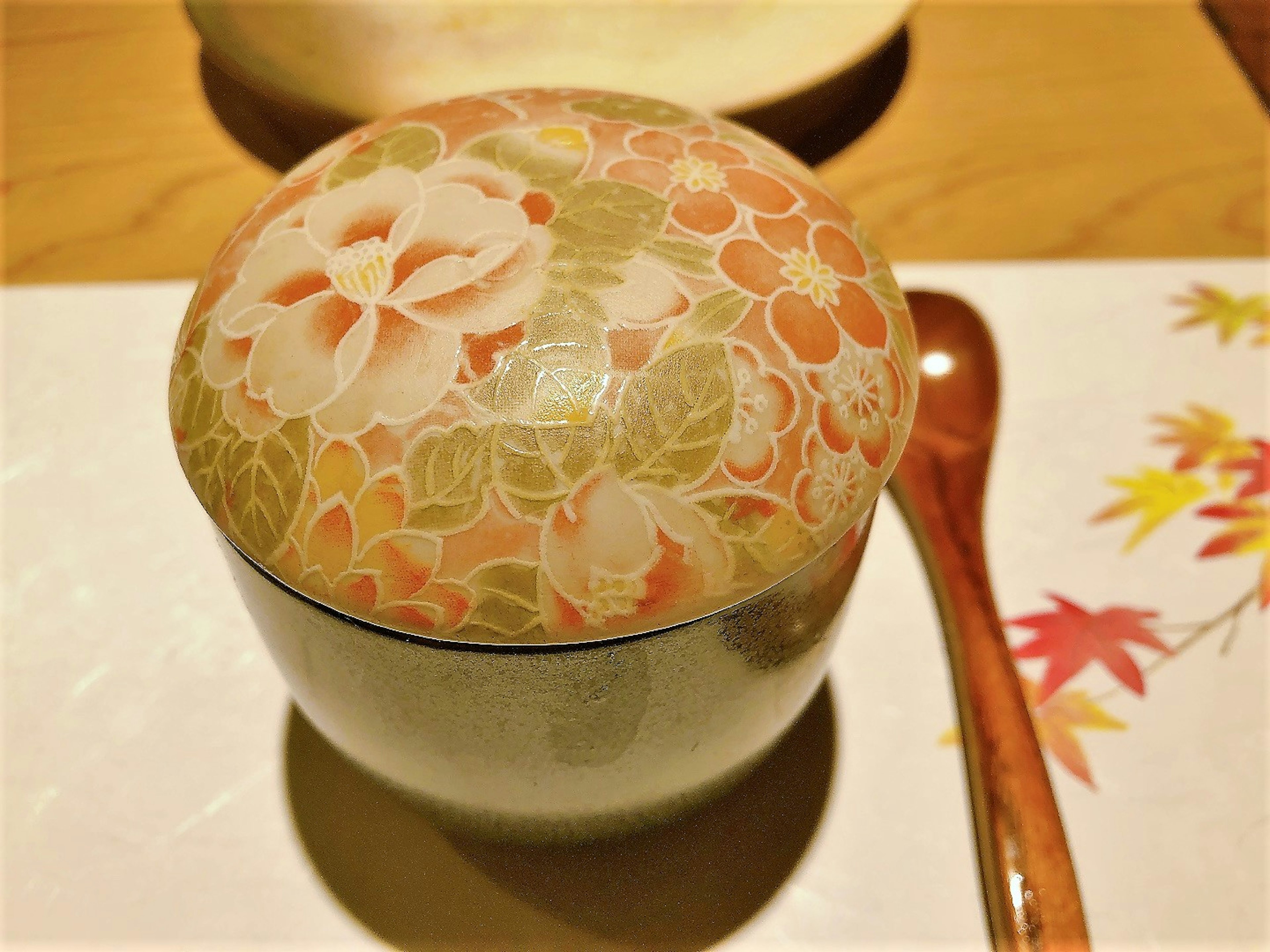 A beautifully patterned Japanese bowl with floral lid and wooden spoon