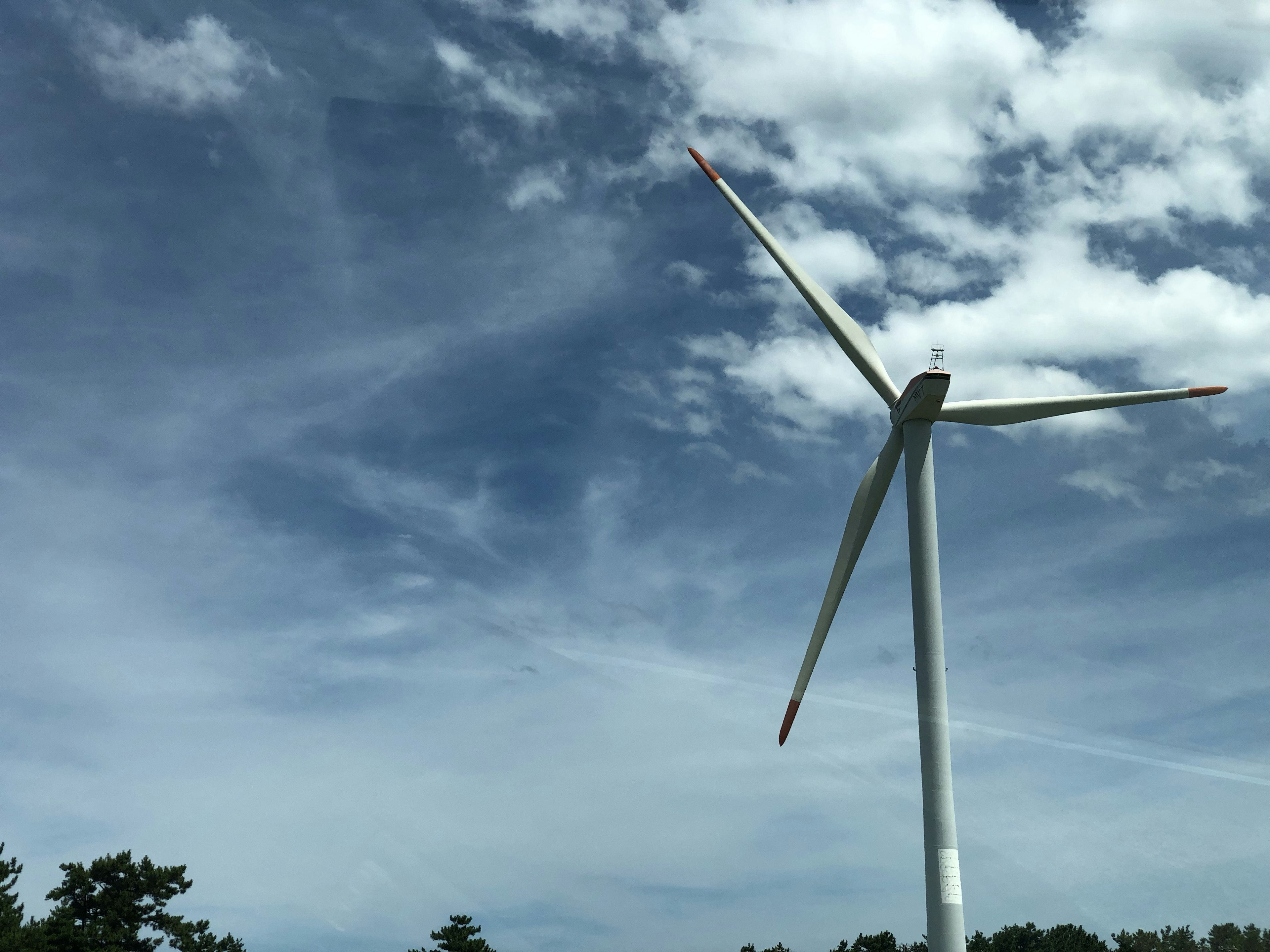 Wind turbine against a blue sky with clouds