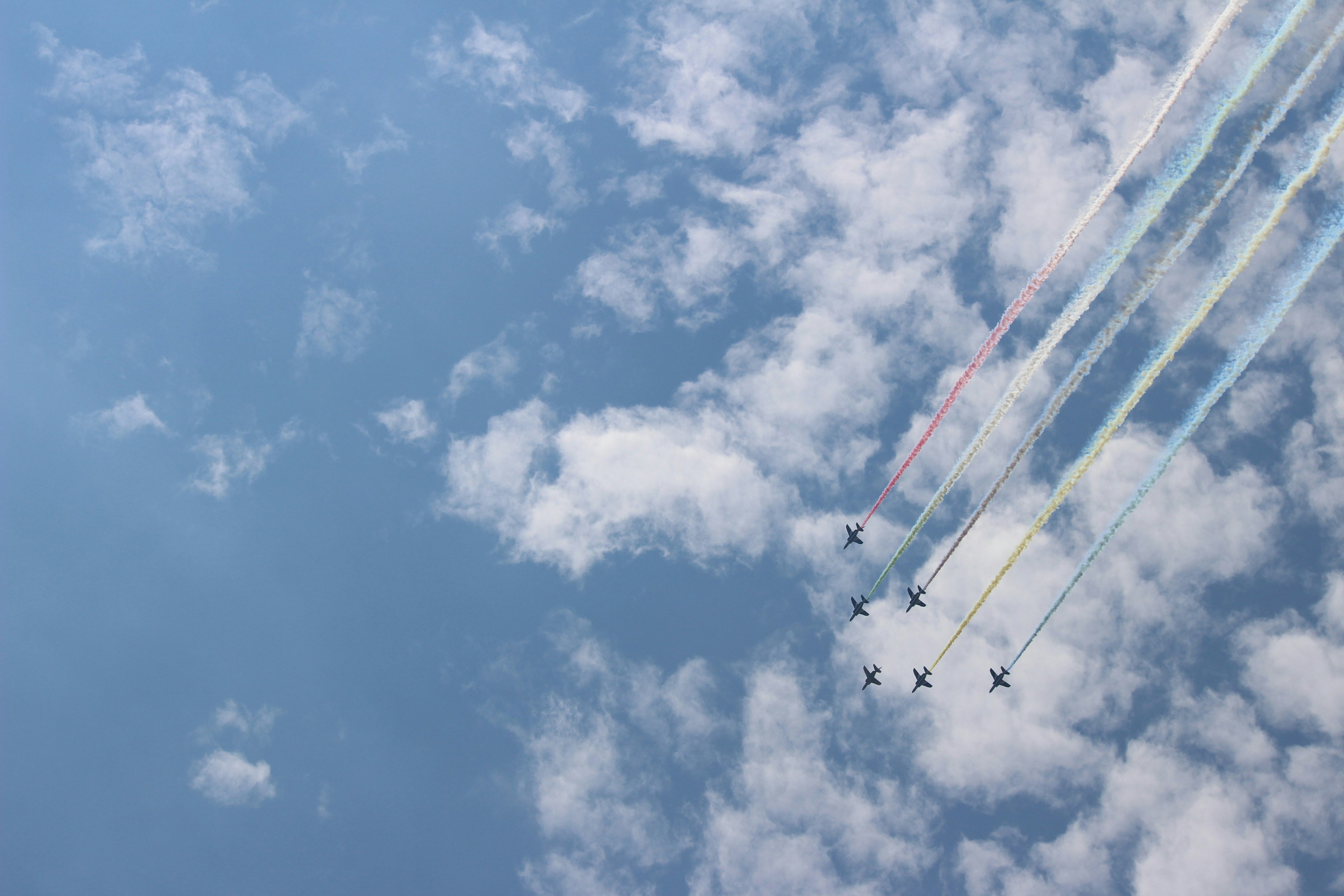 Formation d'avions laissant des traînées de fumée colorées dans le ciel