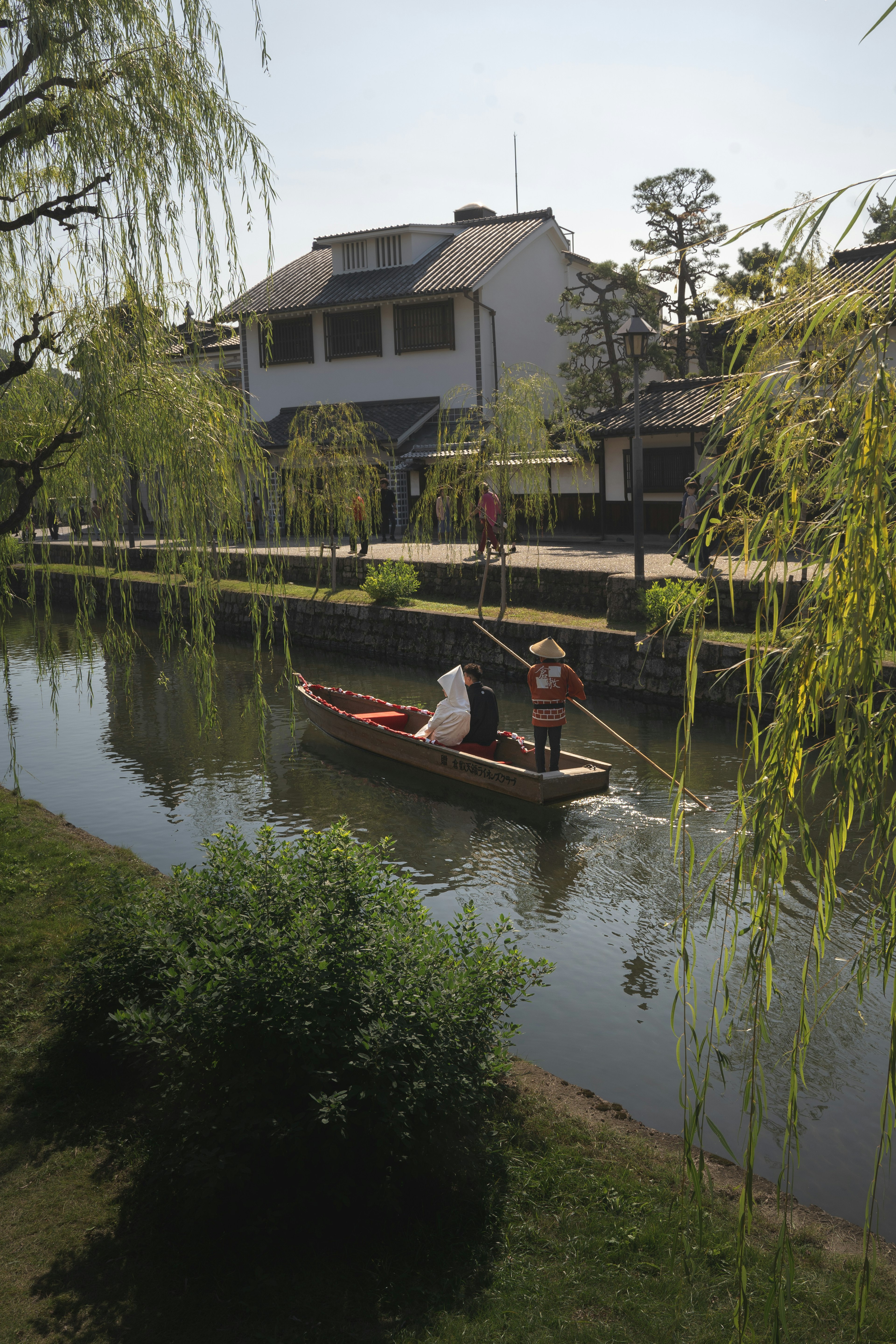 宁静水道上人们在船上的风景，周围有柳树