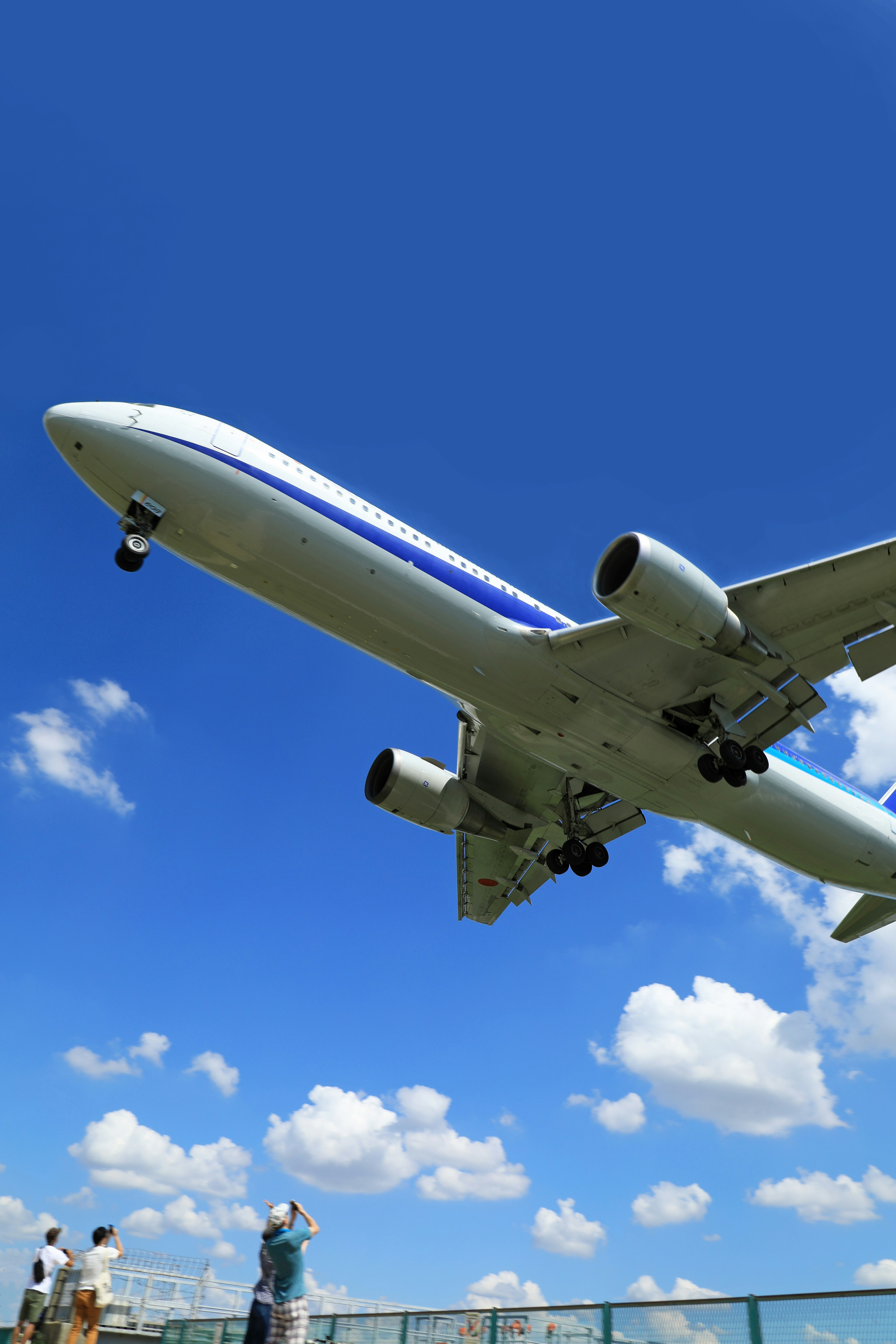 Airplane flying under a clear blue sky with people observing