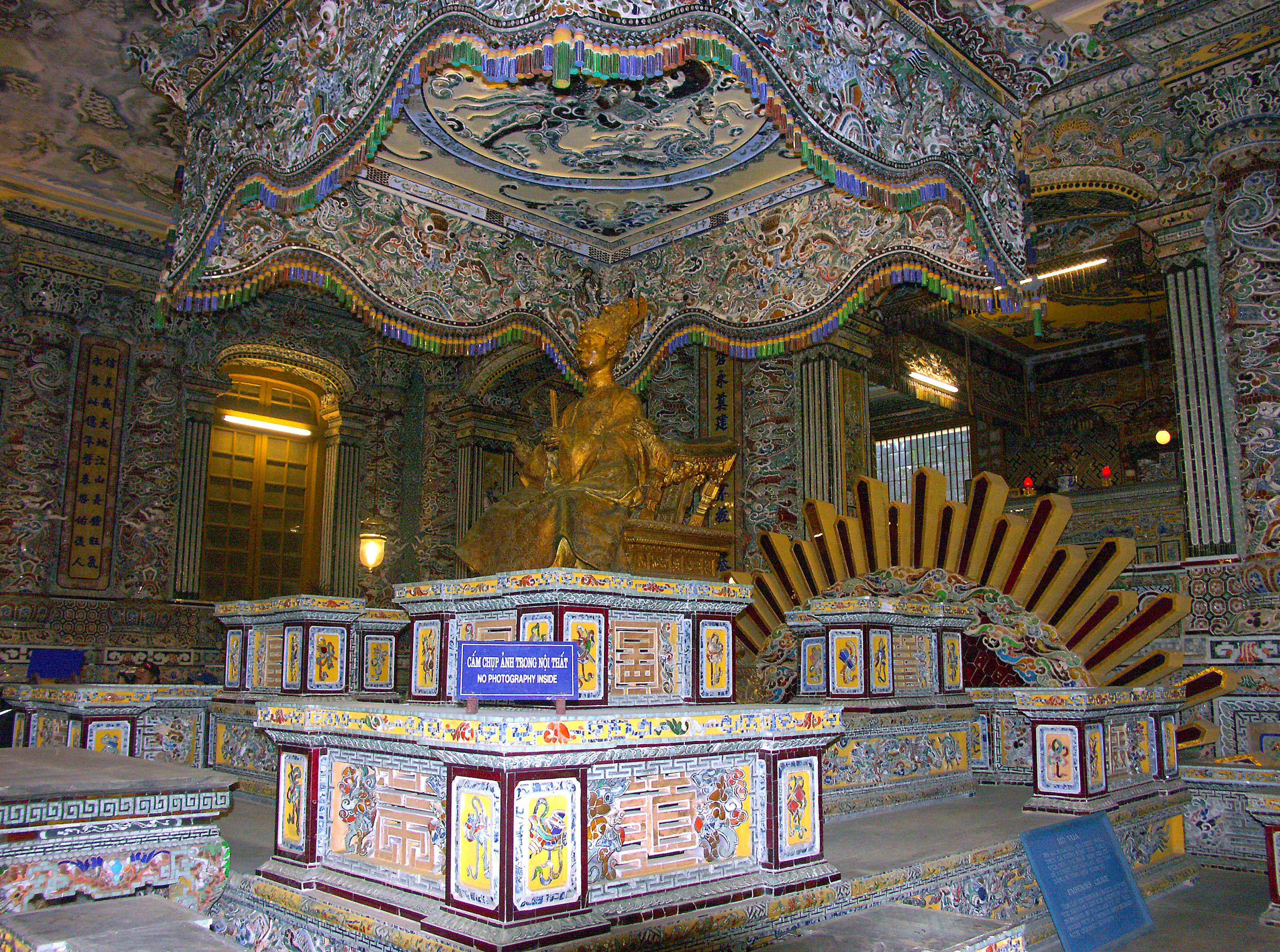 Interior of a temple featuring a golden statue and ornate ceiling decorations