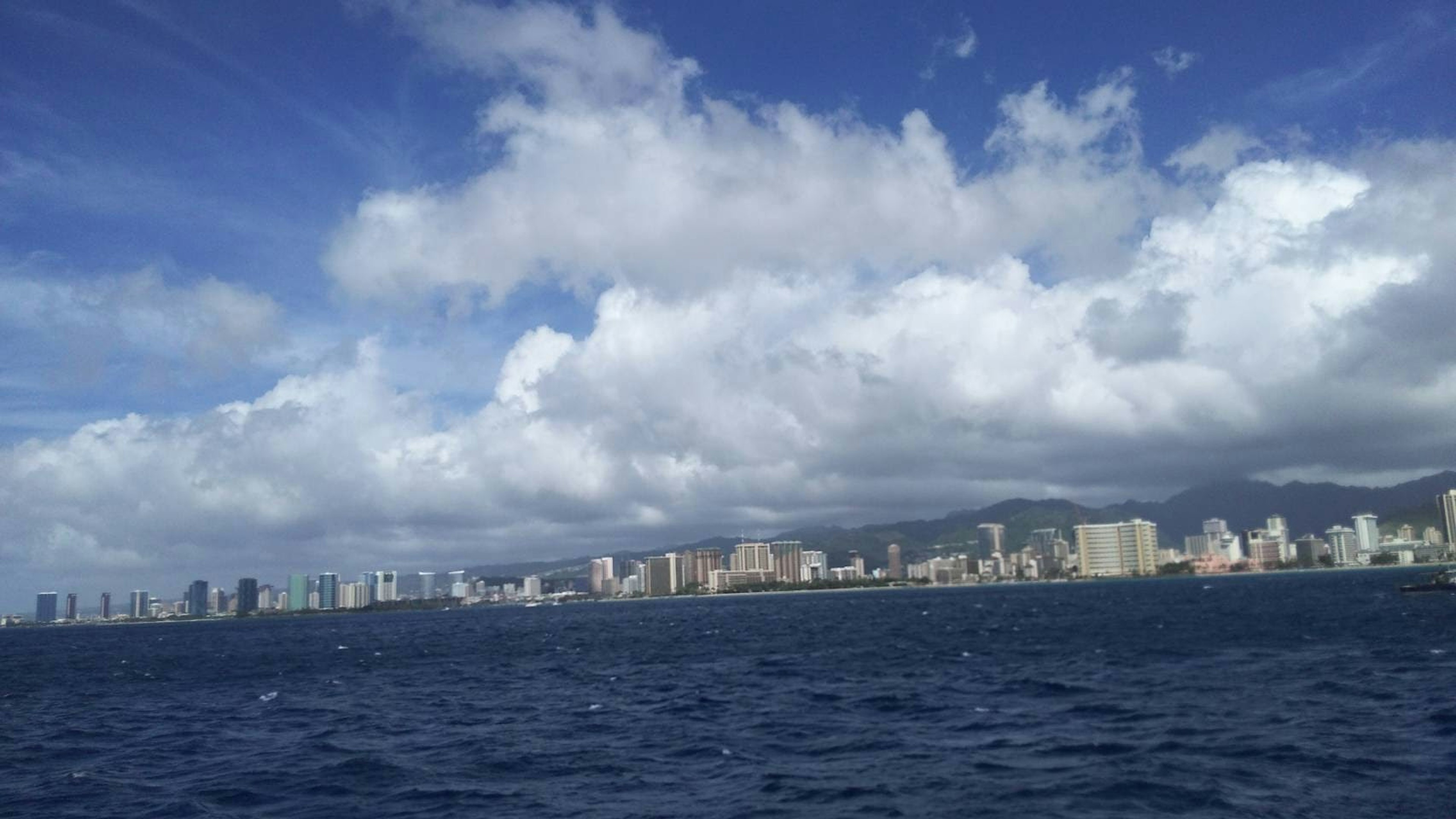 Hawaii city skyline with blue ocean and fluffy clouds