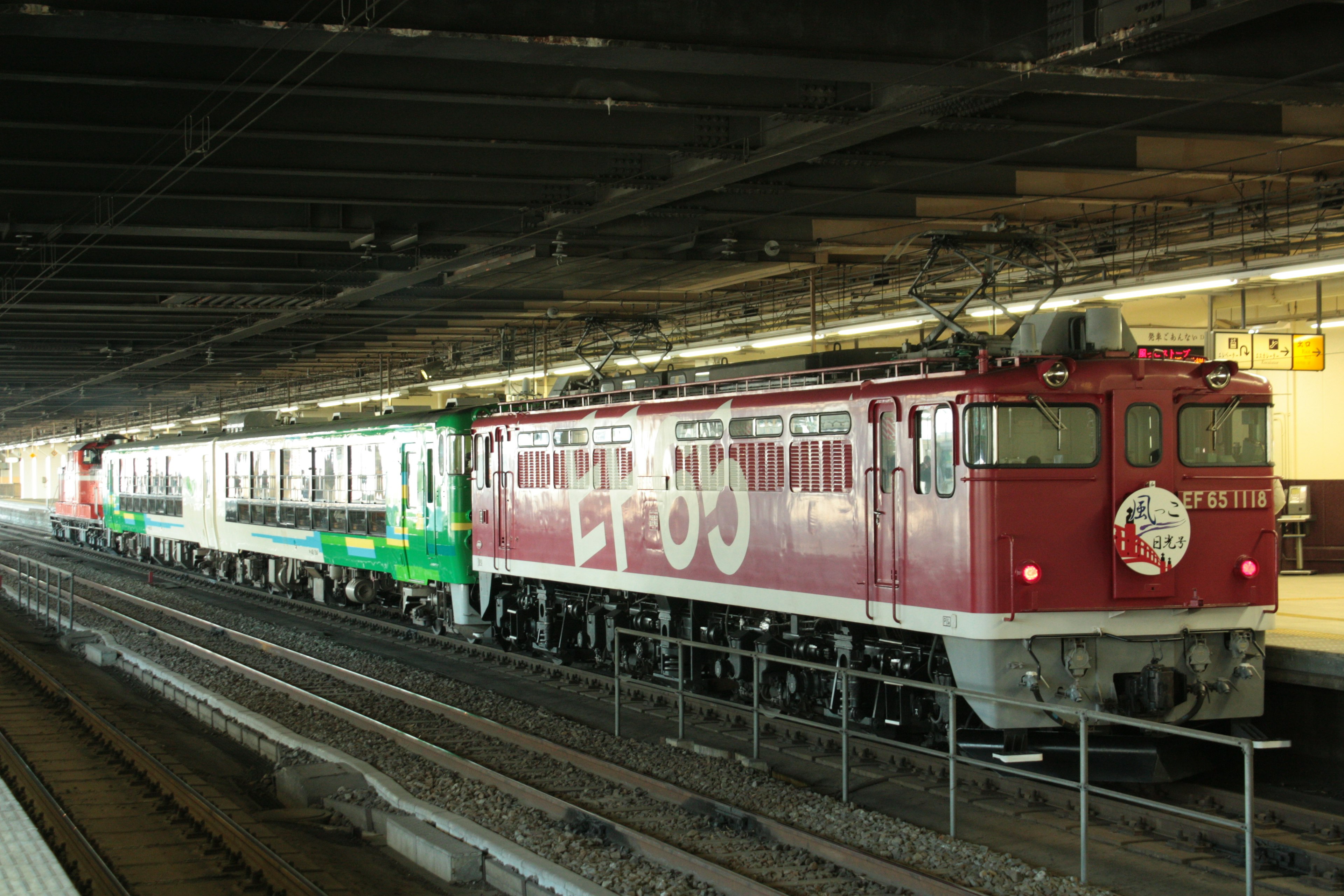 赤い機関車と緑の客車が並ぶ駅の風景