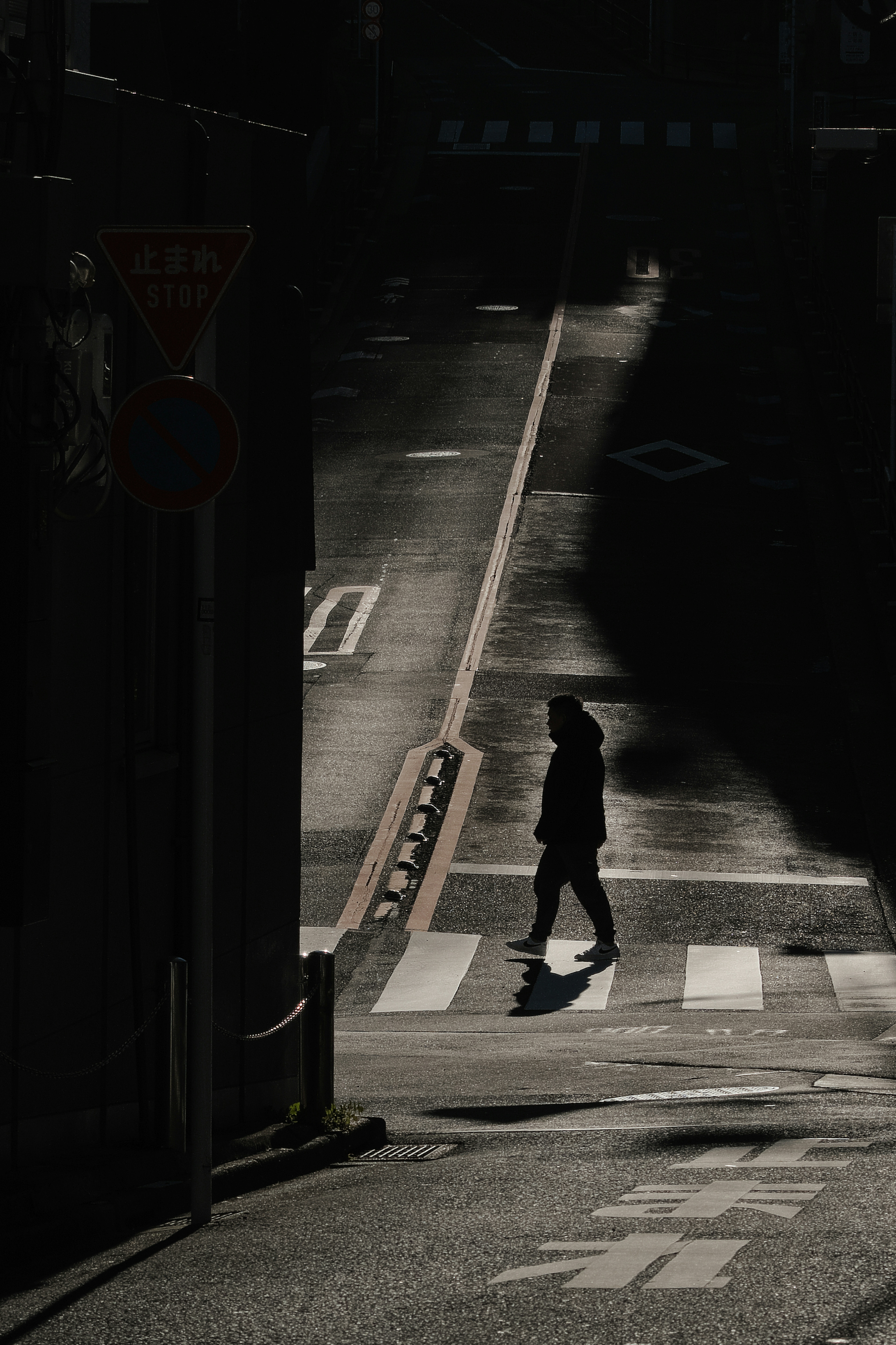 Silhouette einer Person, die im Schatten auf einer Stadtstraße geht