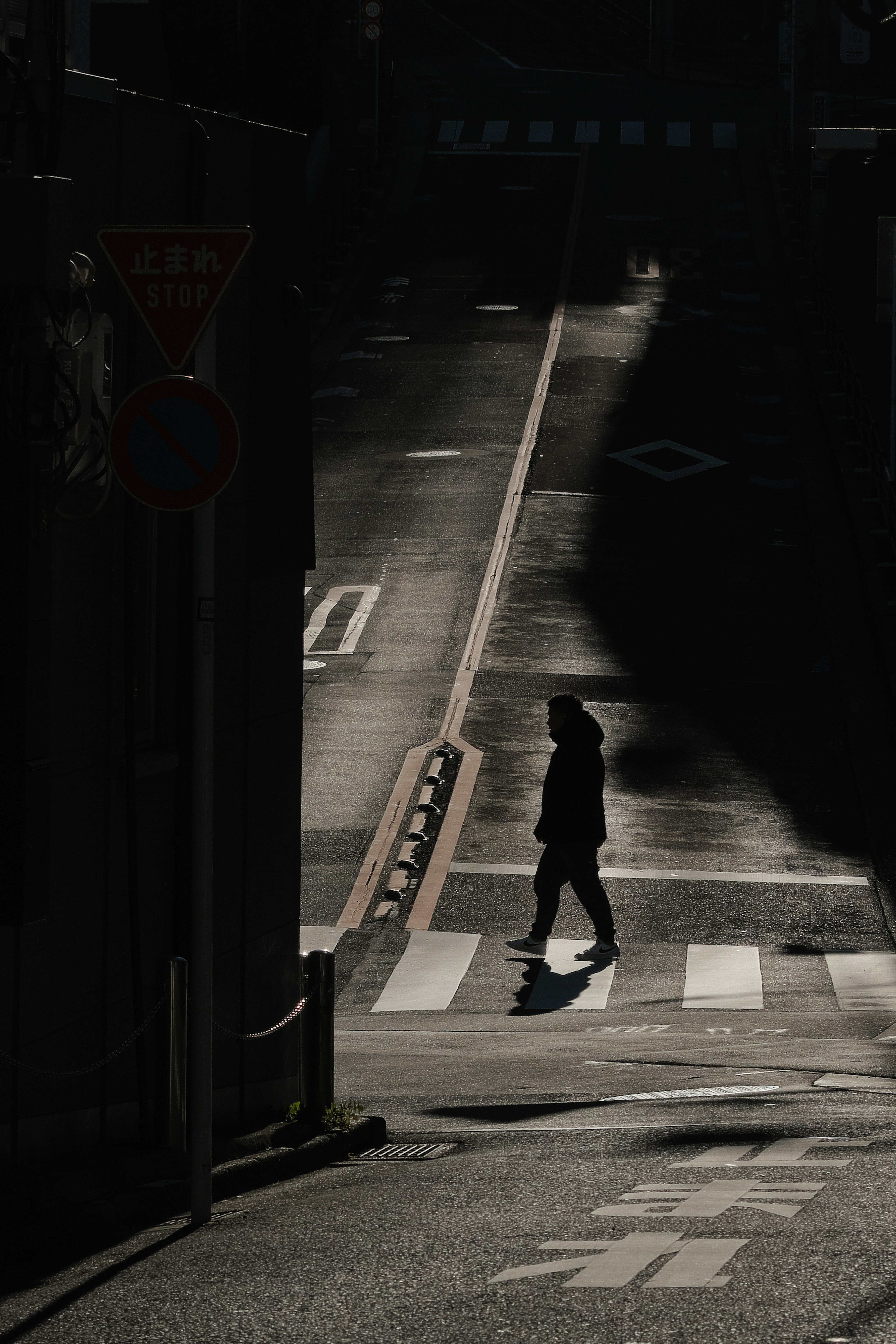 Silhouette of a person walking in the shadows on a city street