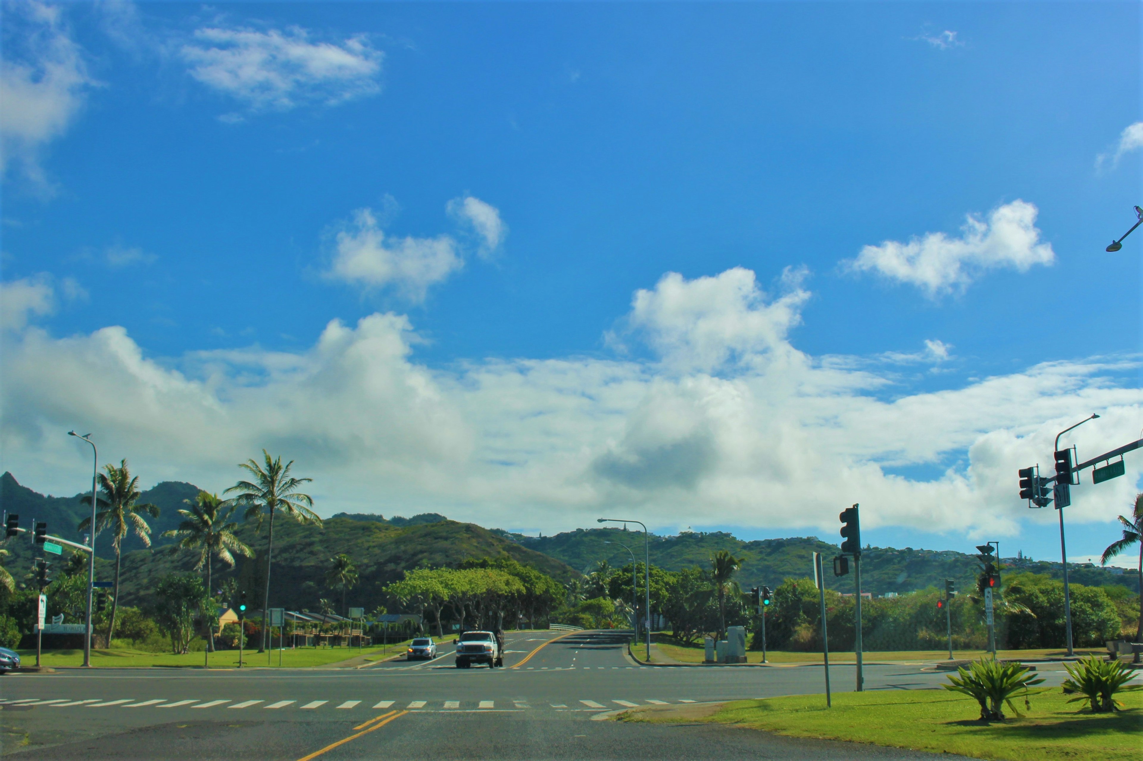 Scenic view of blue sky with white clouds green hills and traffic signals at an intersection