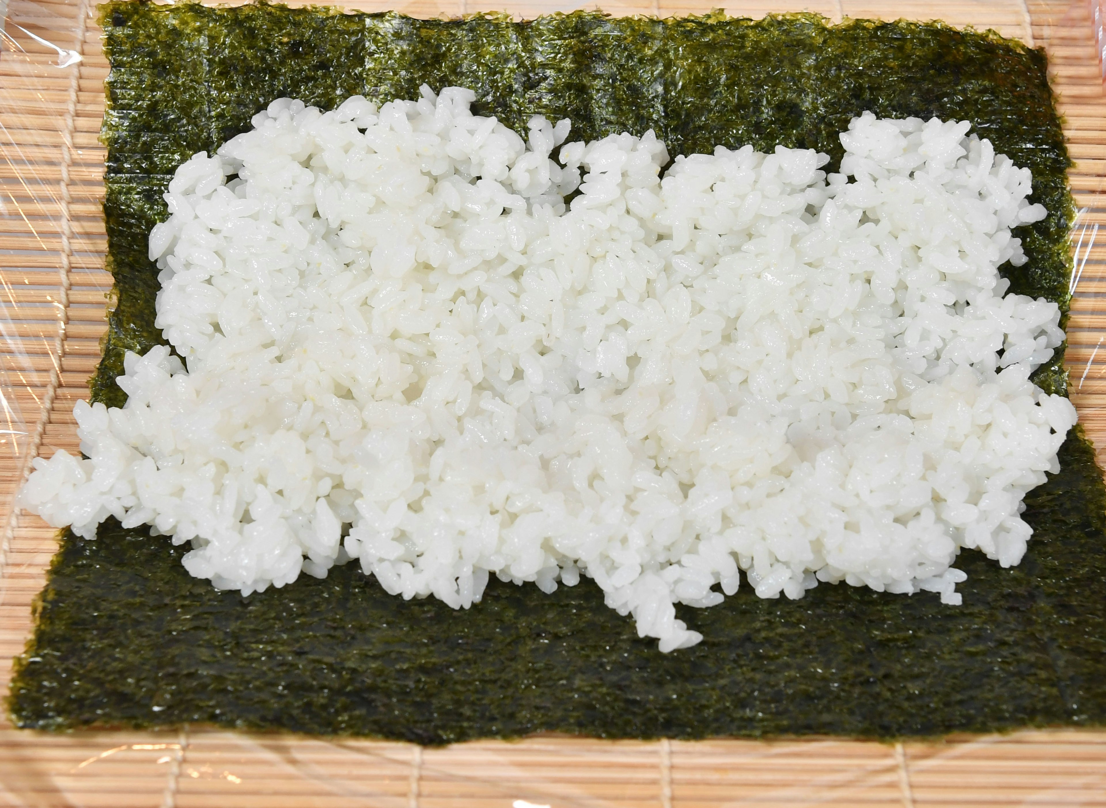 海苔の上に広げられた白いご飯の画像