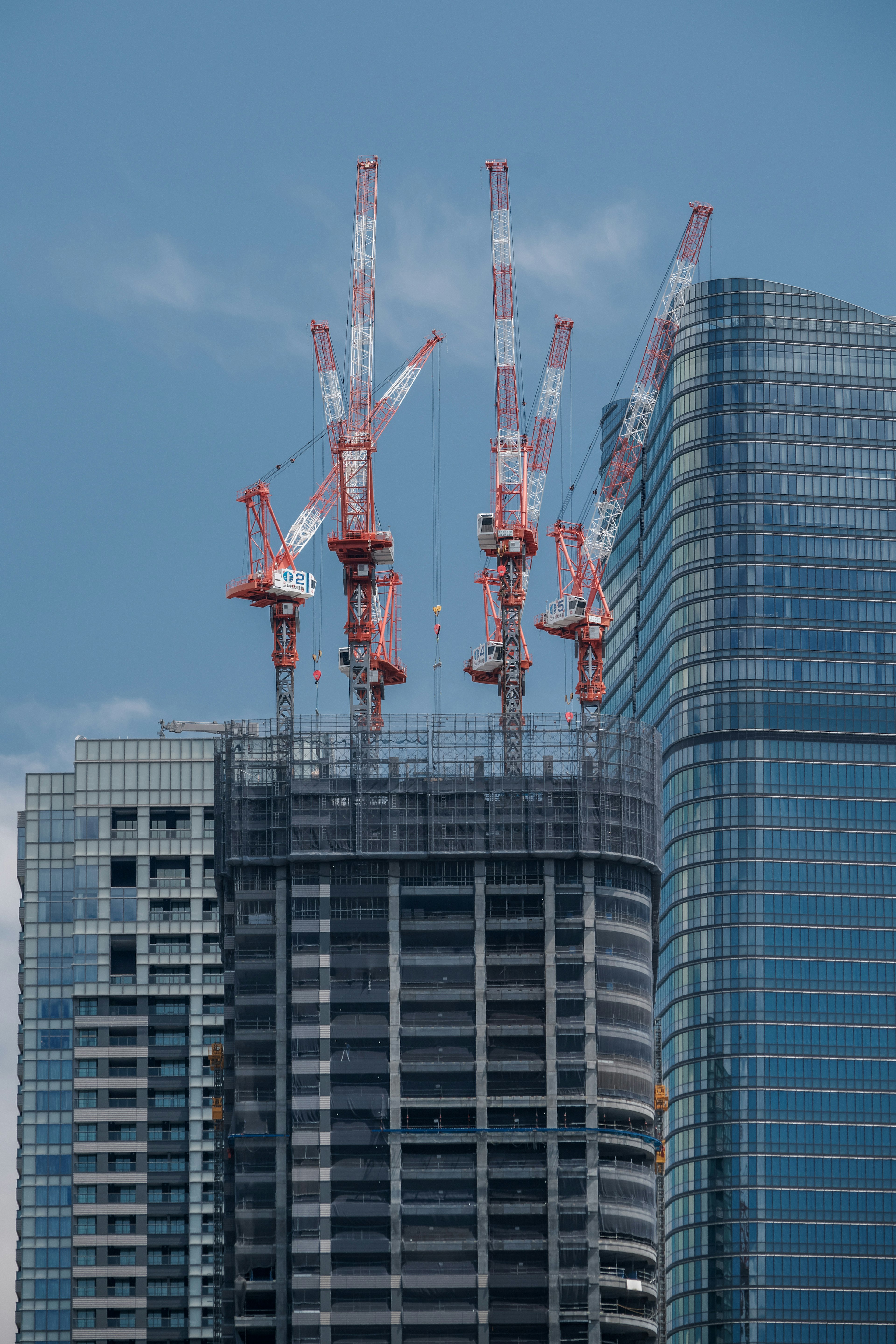 Construction site of a skyscraper with multiple red cranes