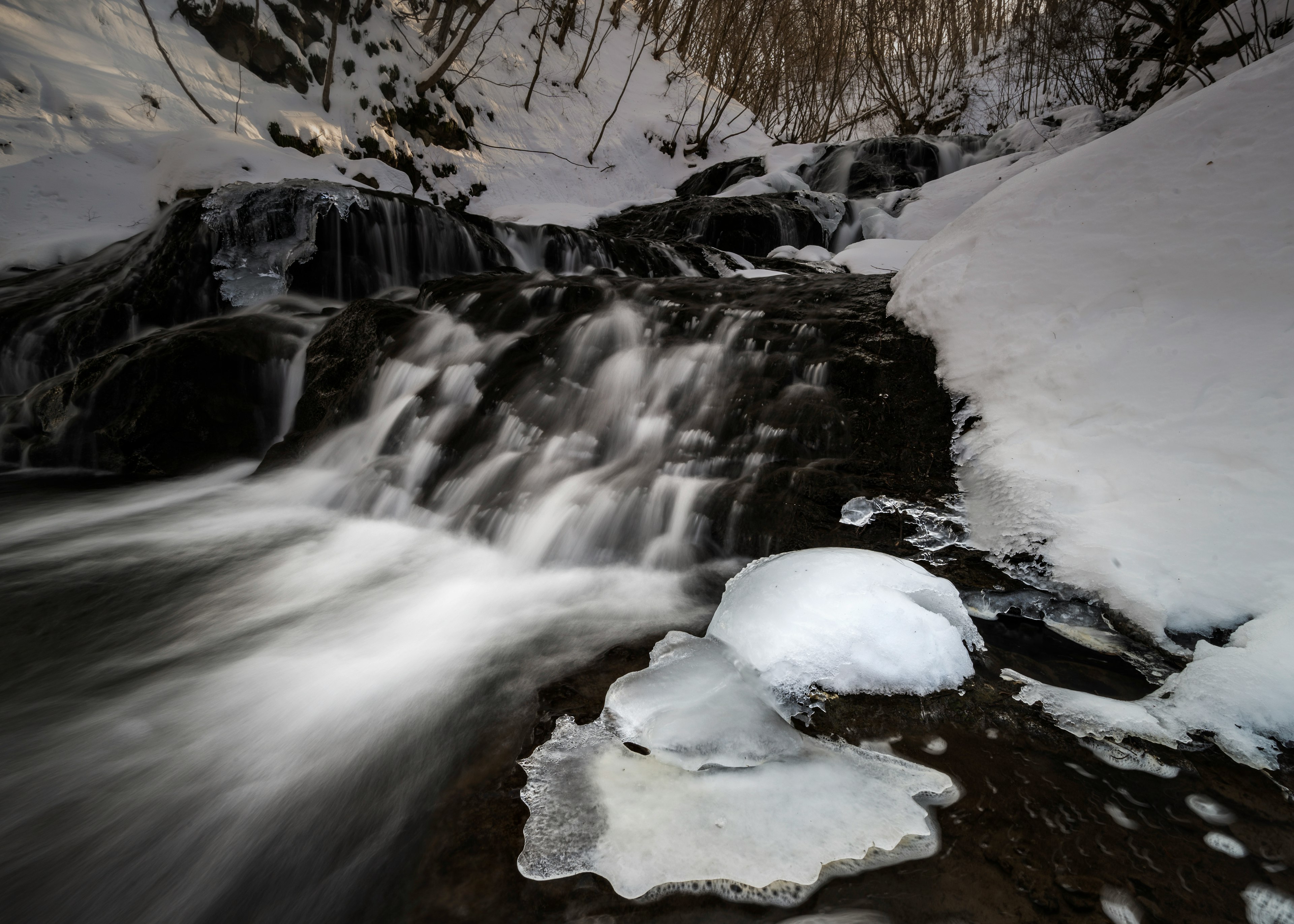 Paesaggio invernale con un fiume che scorre e formazioni di ghiaccio