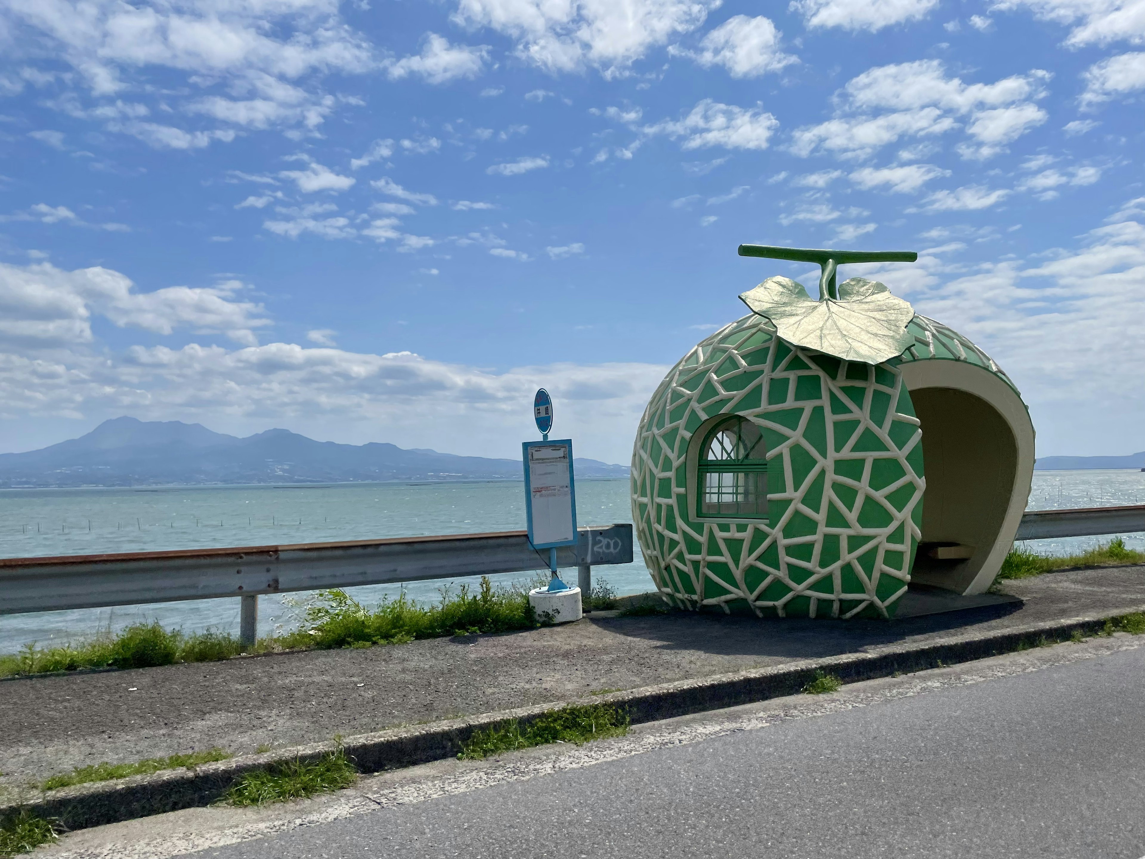 海に面したユニークな果物の形のバス停 緑色のデザインと周囲の自然