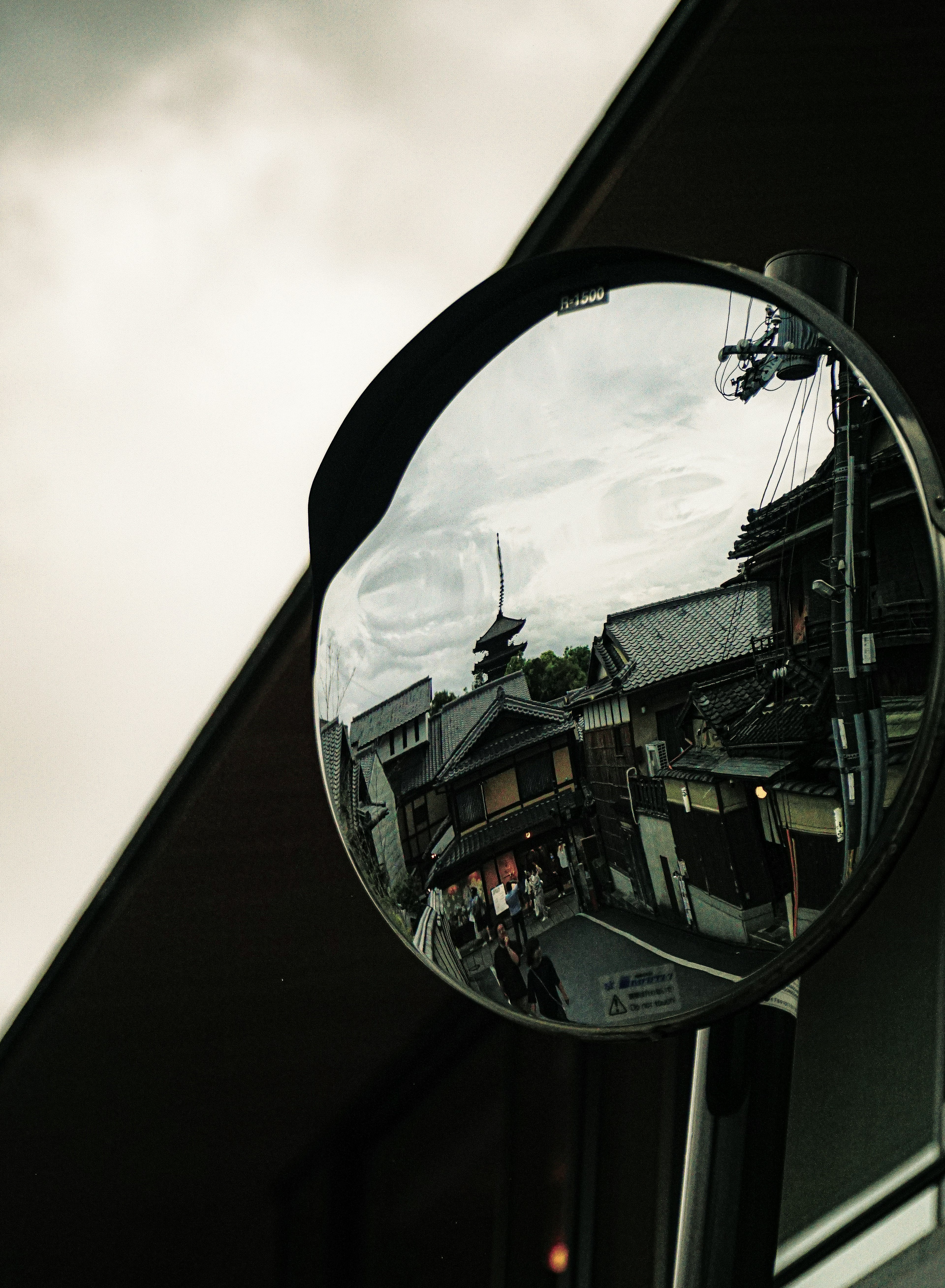 Round mirror reflecting cityscape with cloudy sky