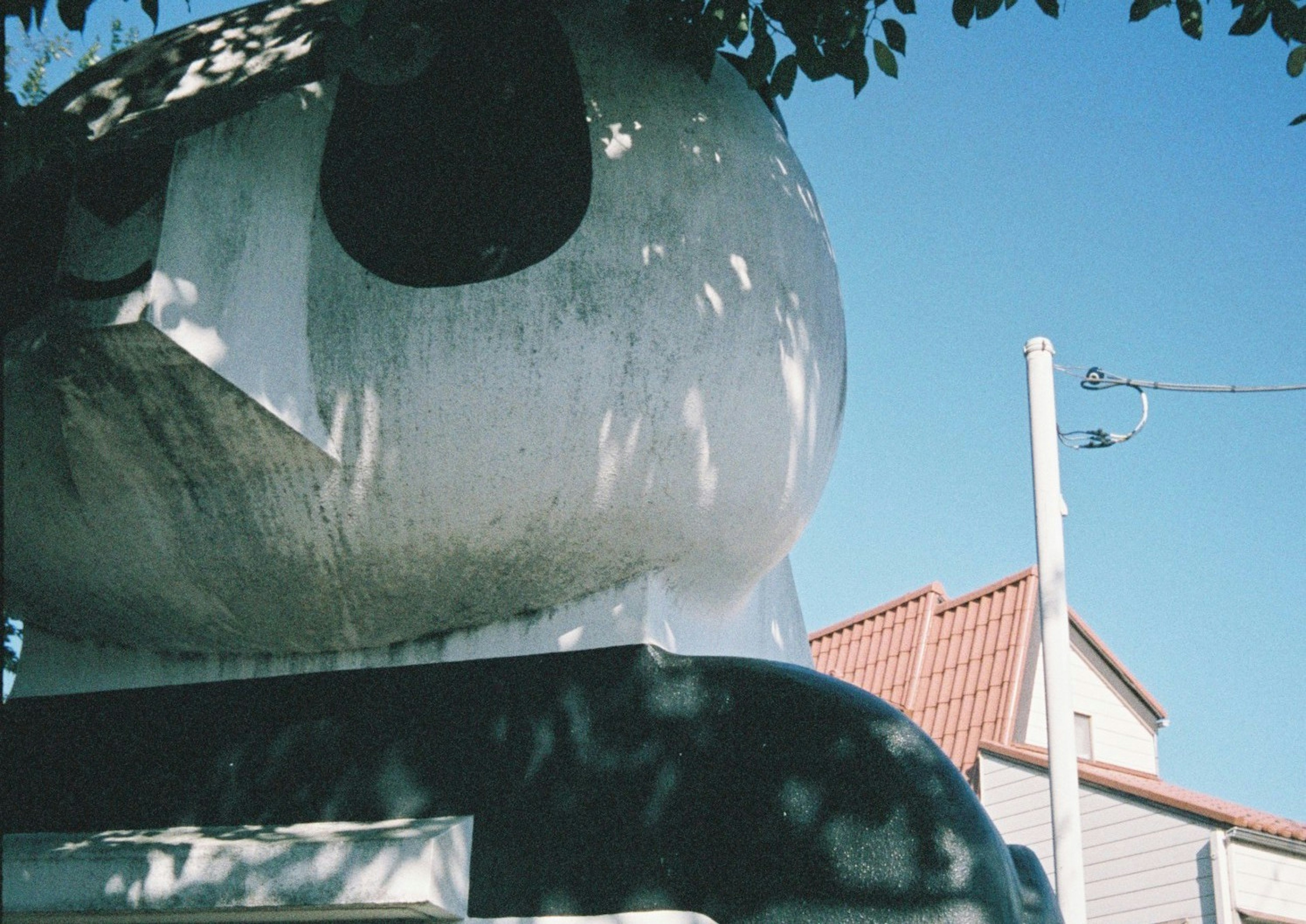 Large white sculpture with a black face against a blue sky