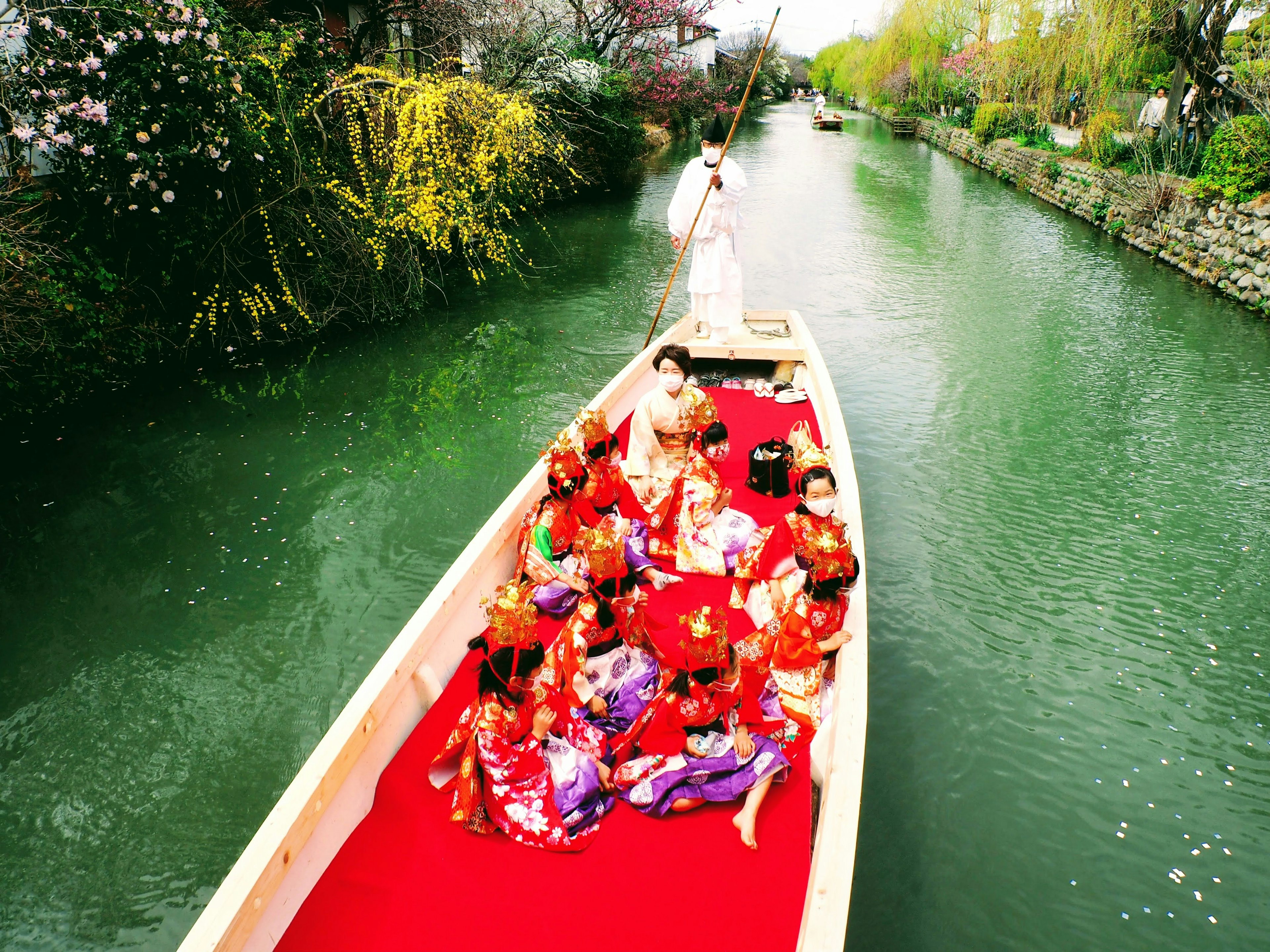 Grupo de mujeres en kimonos coloridos en un bote en un canal verde