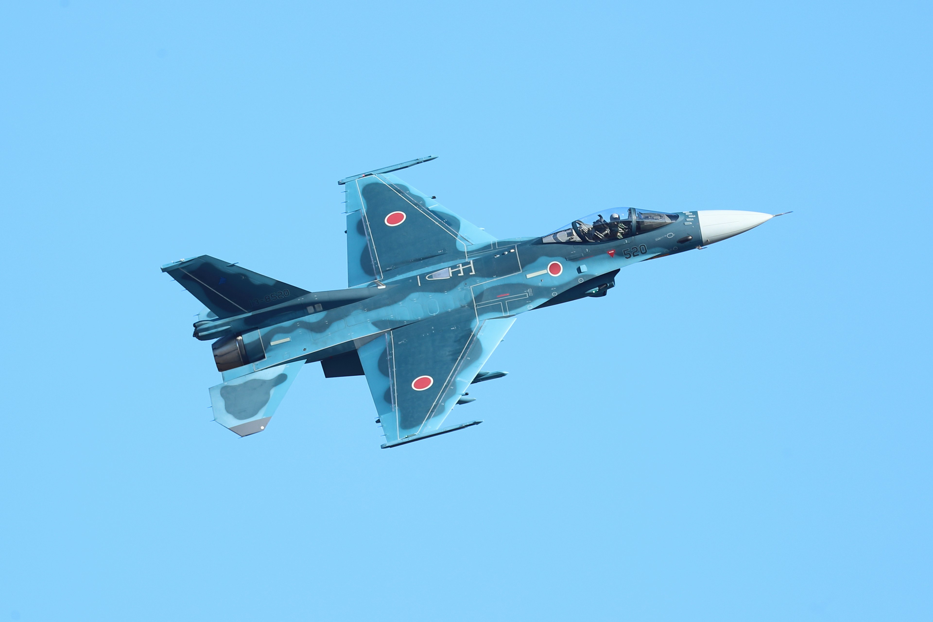 Top view of a blue fighter jet flying in the sky