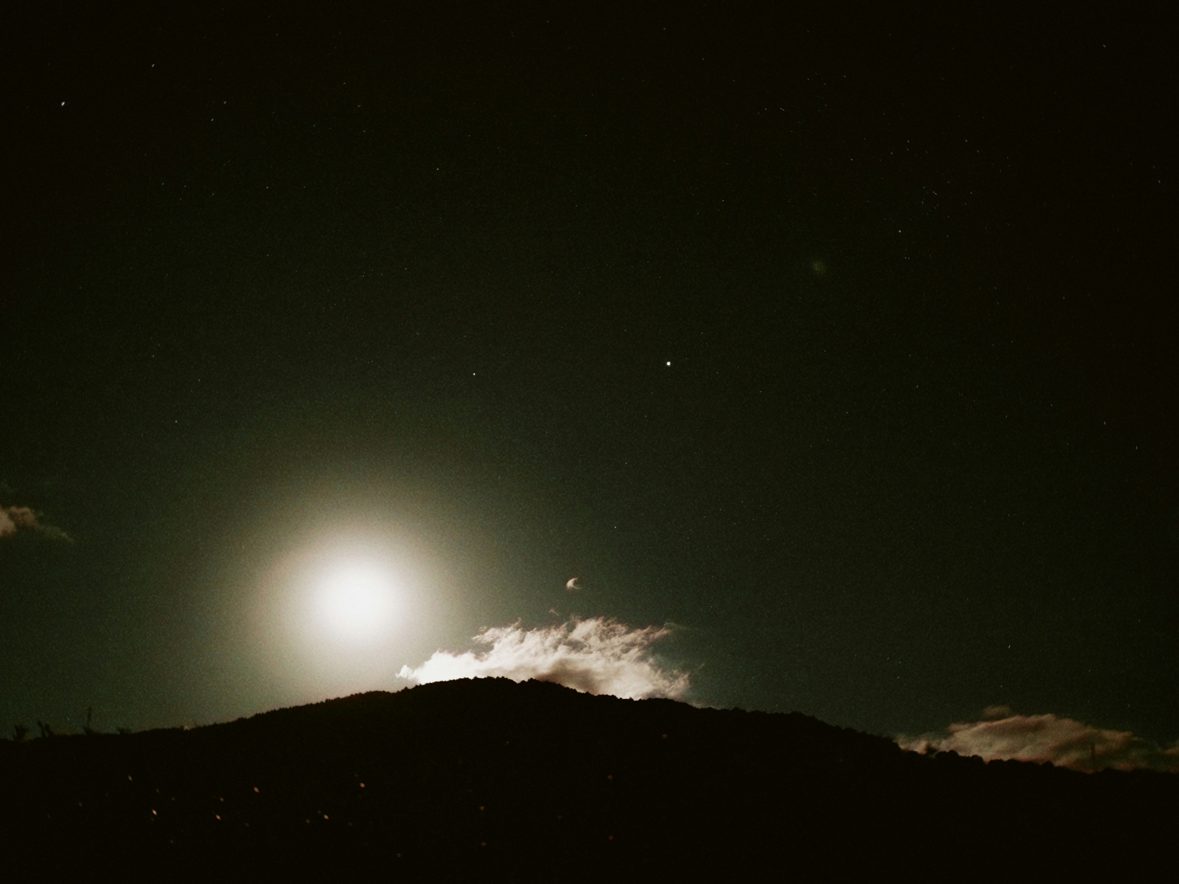 Lune pleine illuminant le ciel nocturne avec une silhouette de montagne