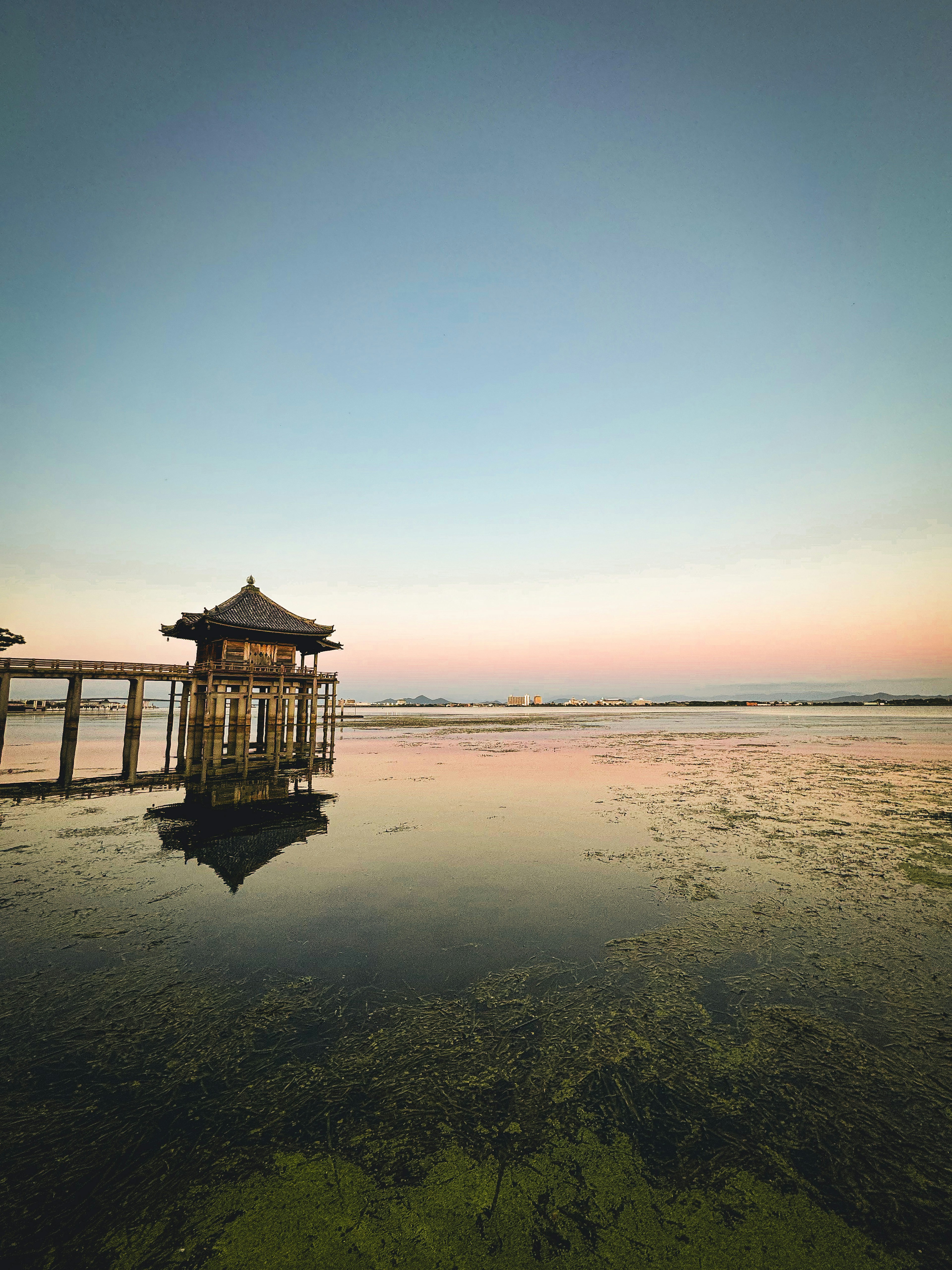 水に映る小屋と夕焼けの空が広がる海の風景