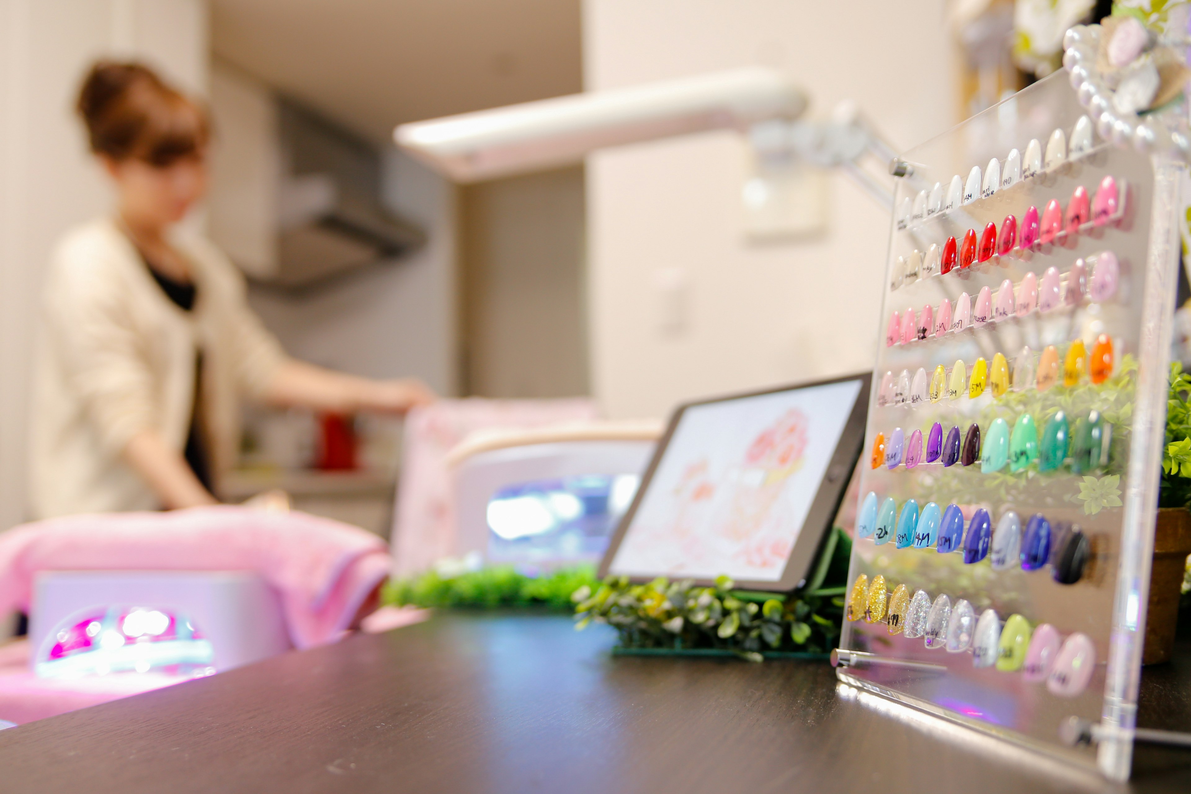 Intérieur d'un salon de nail art avec des vernis à ongles colorés et une femme au travail