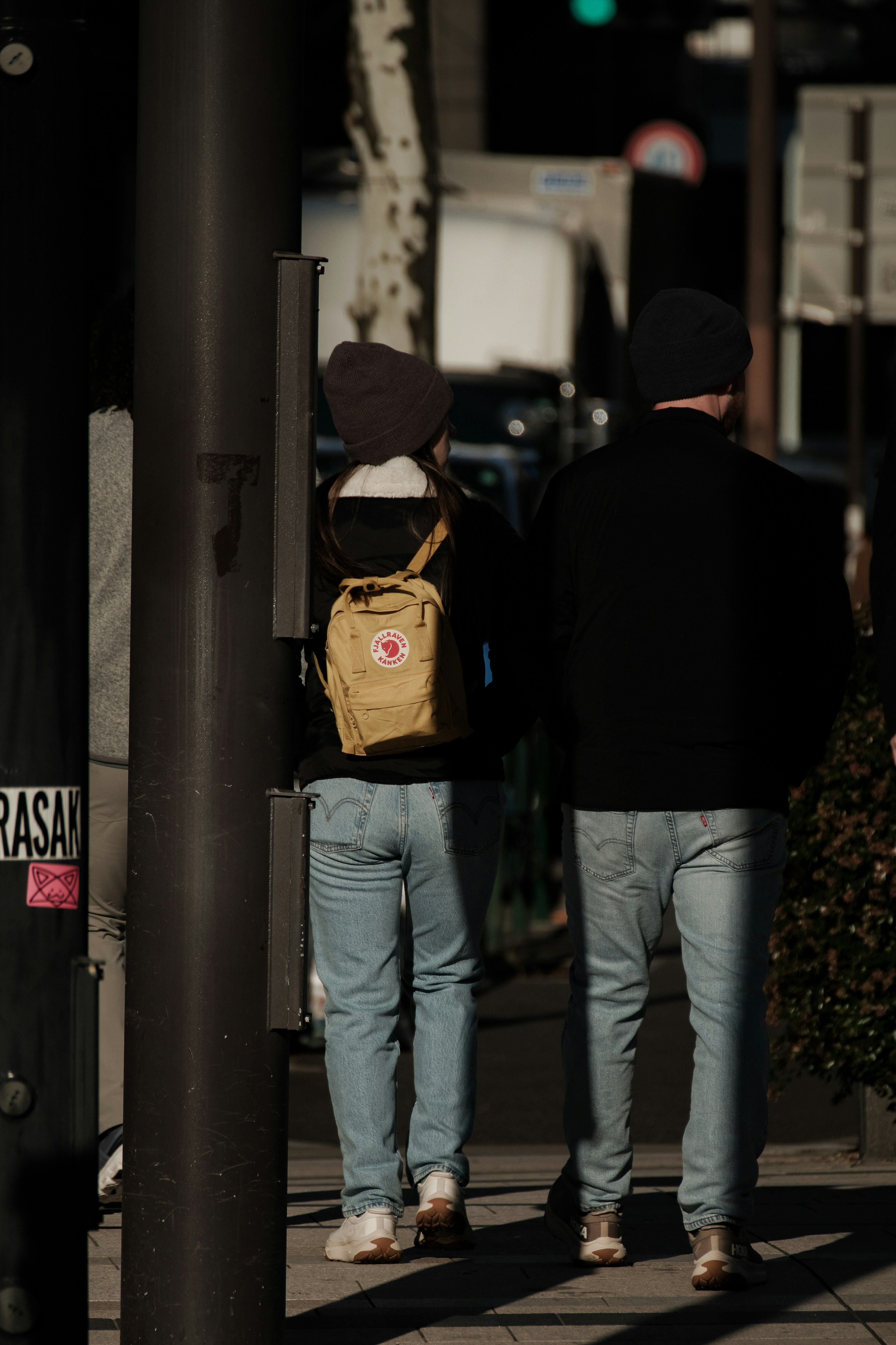 2人の人物が街を歩いている後ろ姿 黄色いバックパックを持っている人がいる