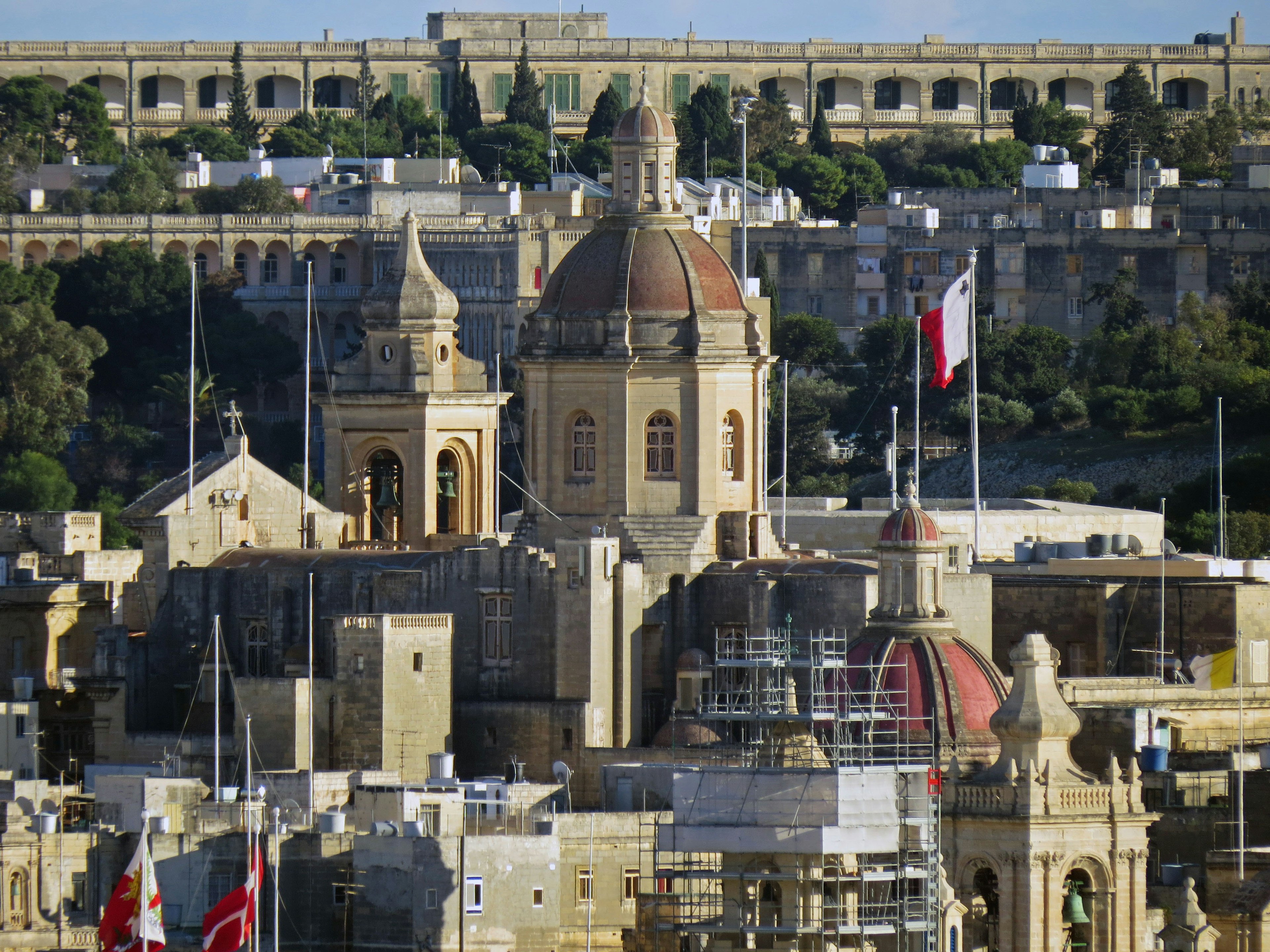 Blick auf ein Gebäude in Malta mit einer Kuppeldach und Nationalflaggen