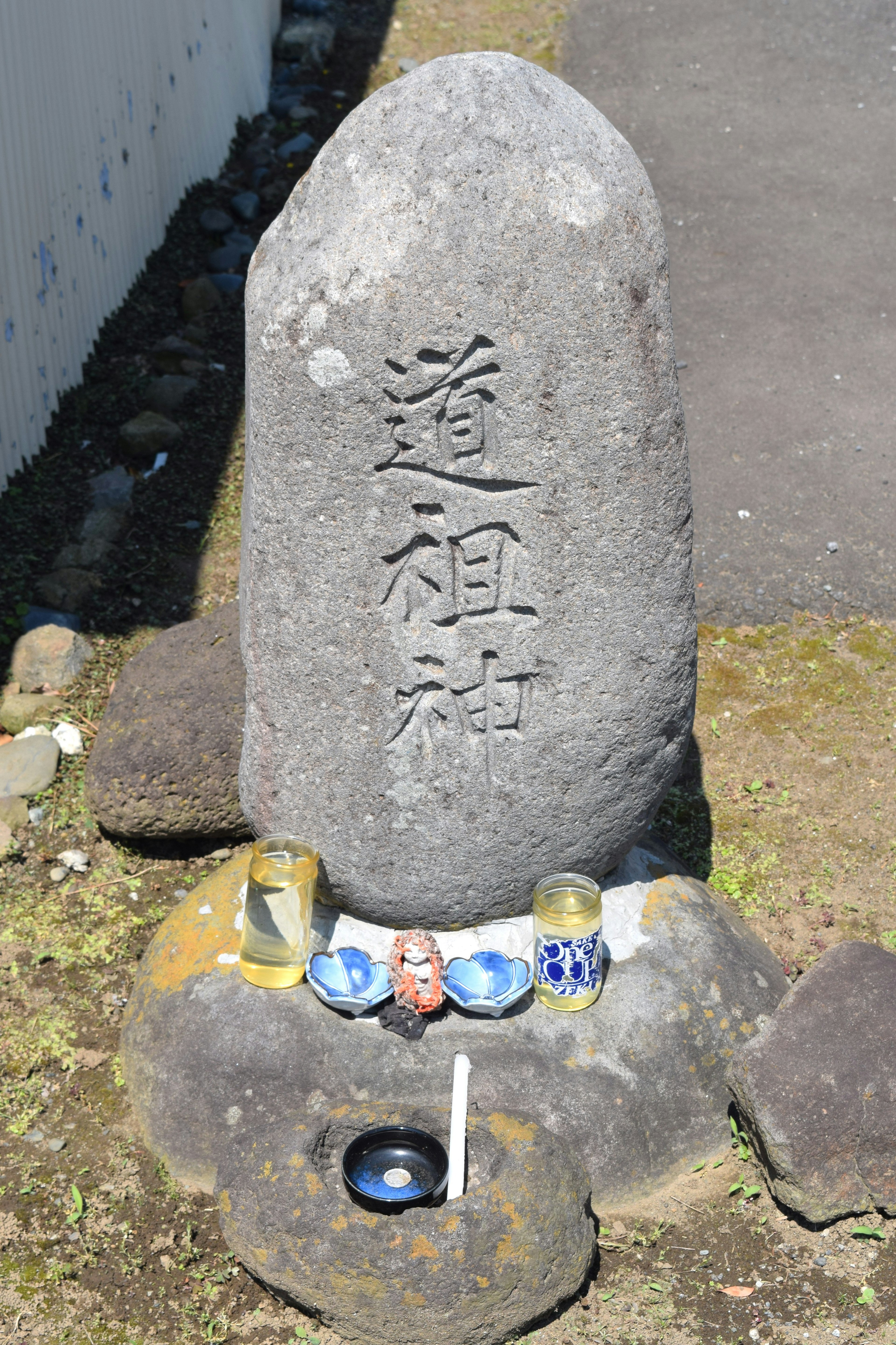 Stone monument with engraved characters and surrounding offerings