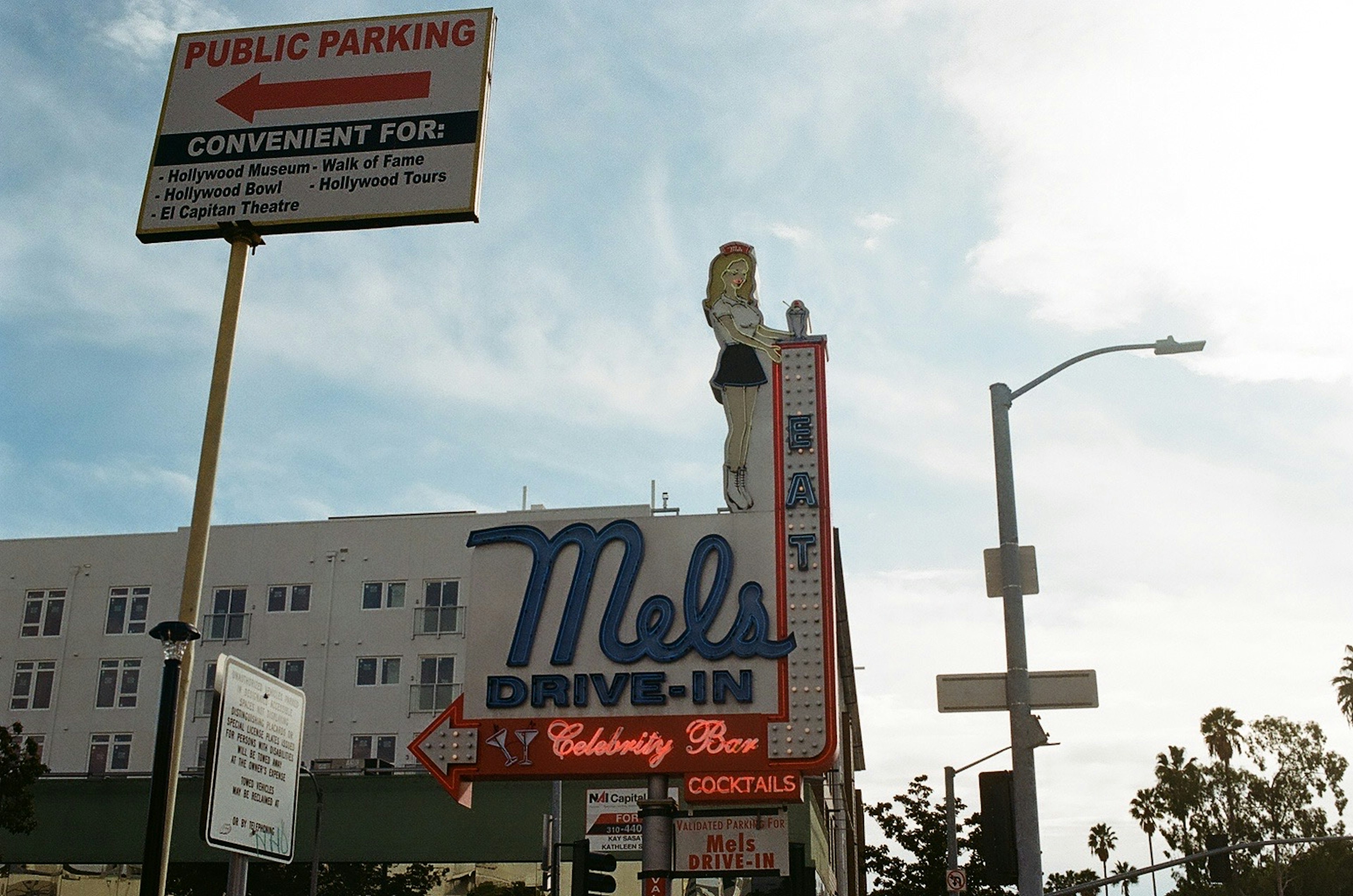 Panneau de Mel's Drive-In avec un panneau de stationnement en arrière-plan