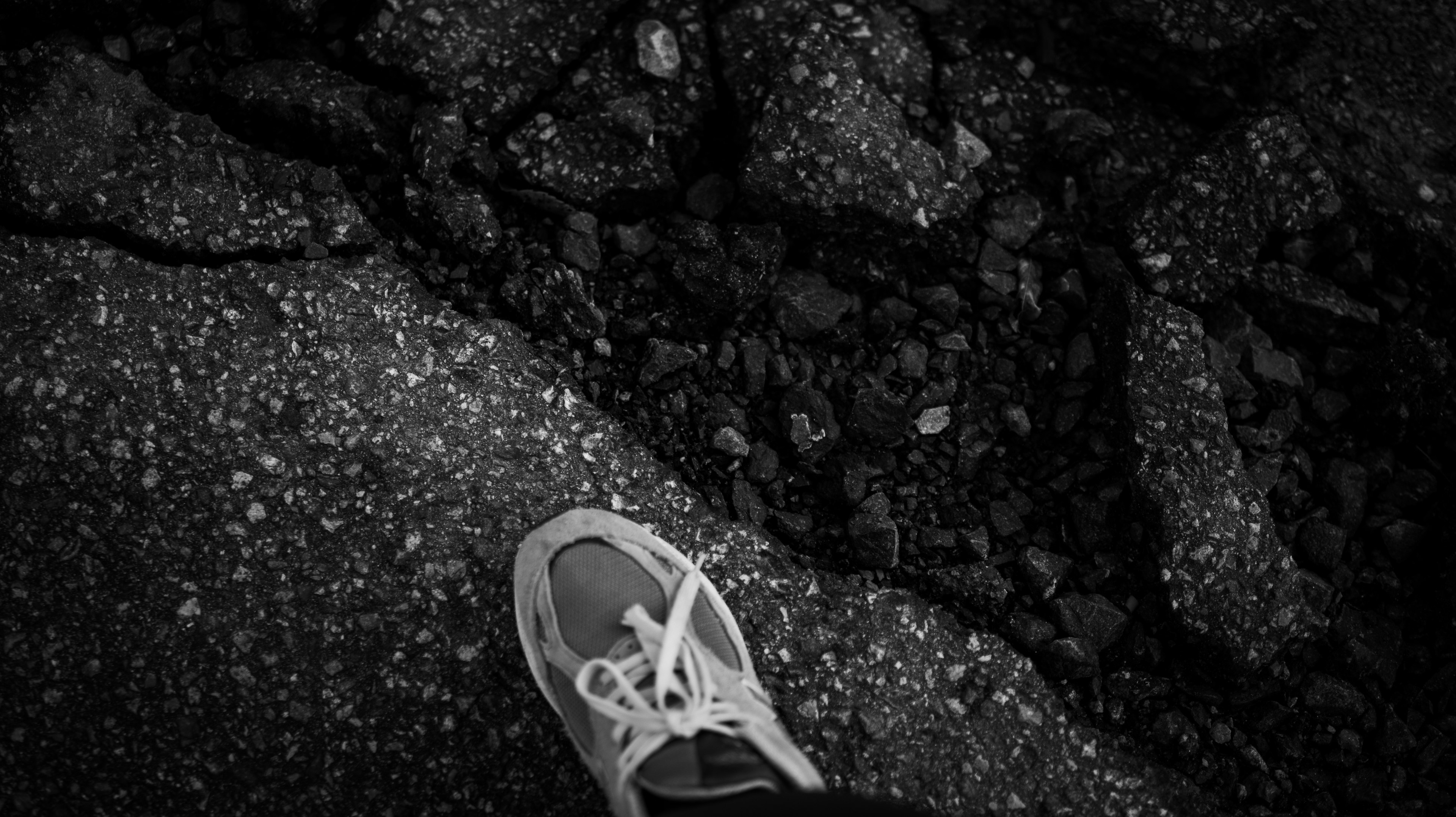 Close-up of a sneaker on cracked pavement in black and white