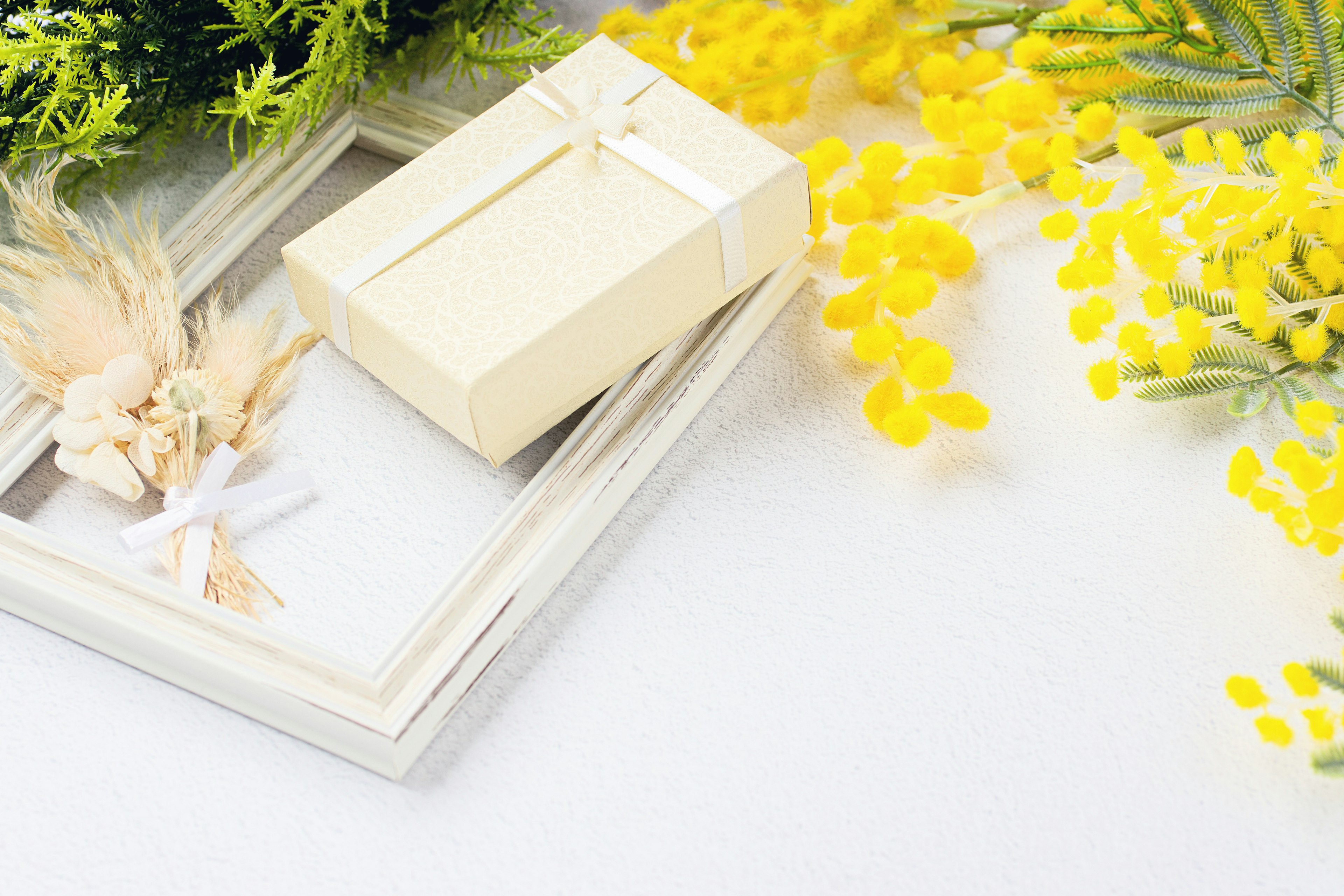 A serene scene featuring a white frame and a gift box near yellow flowers