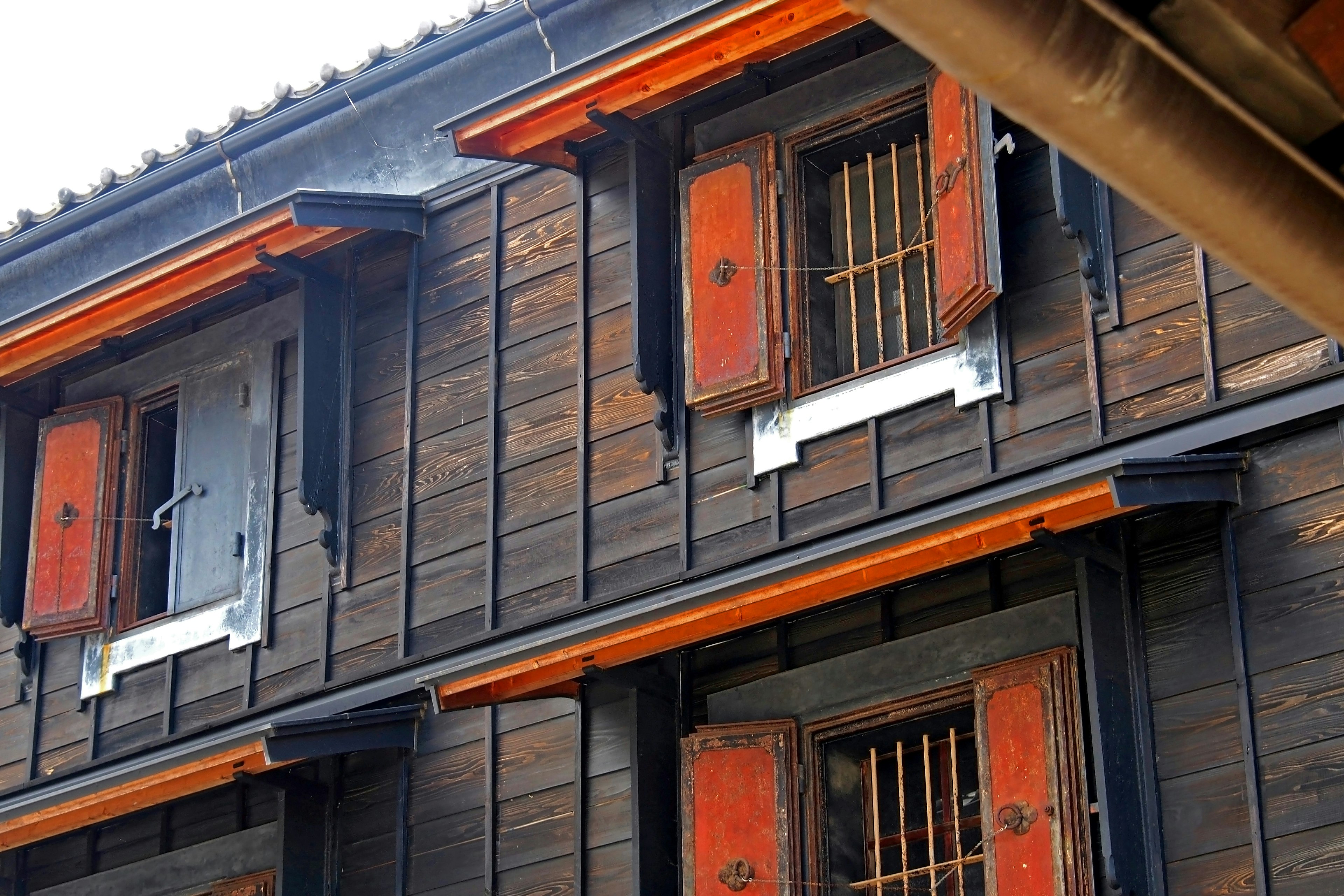 Exterior of a wooden building featuring orange shutters and bars