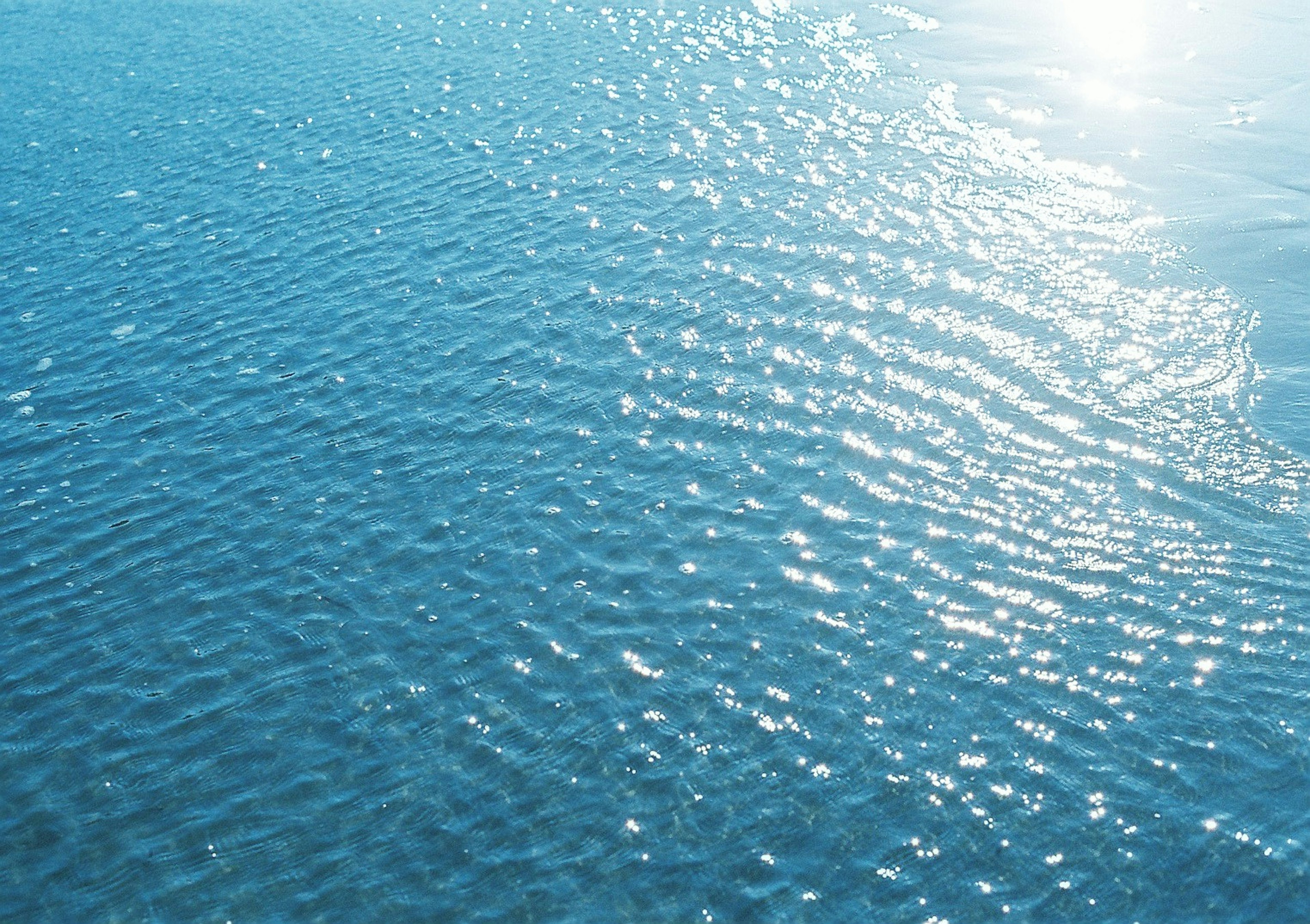 Superficie de agua azul ondulante que refleja la luz