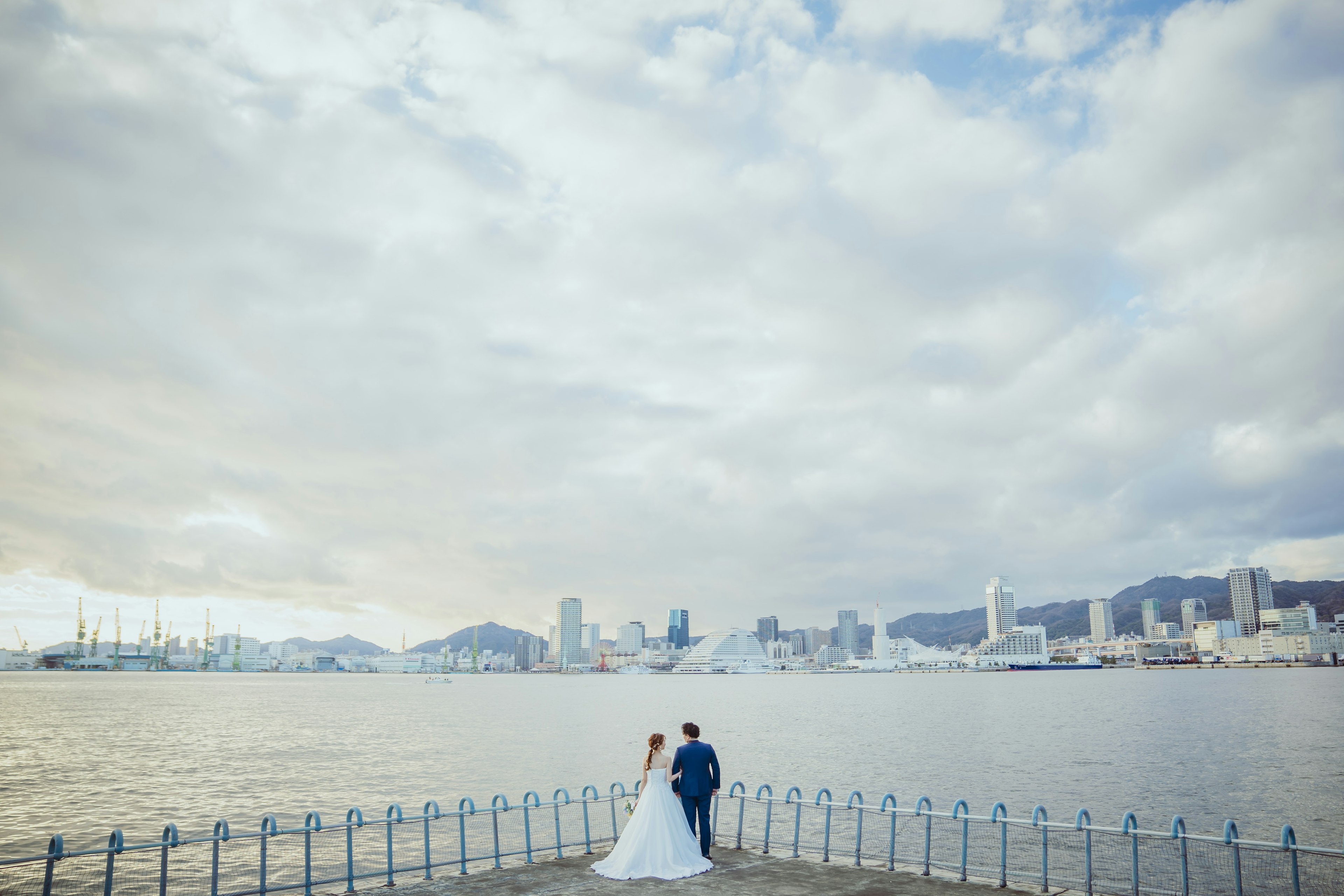 水辺で立つ新郎新婦と都市の背景