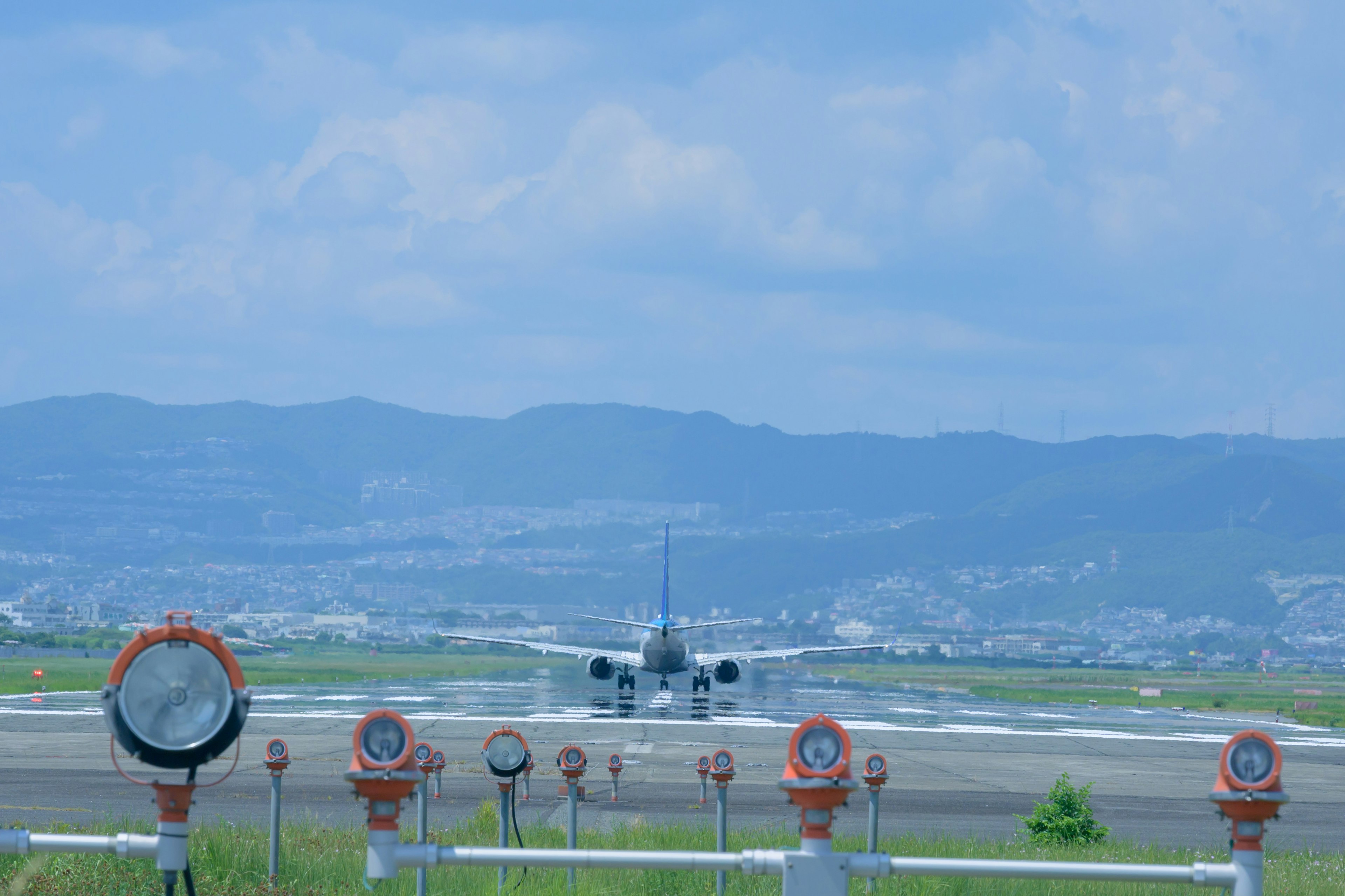 空港の滑走路で離陸する飛行機とその背後の山々