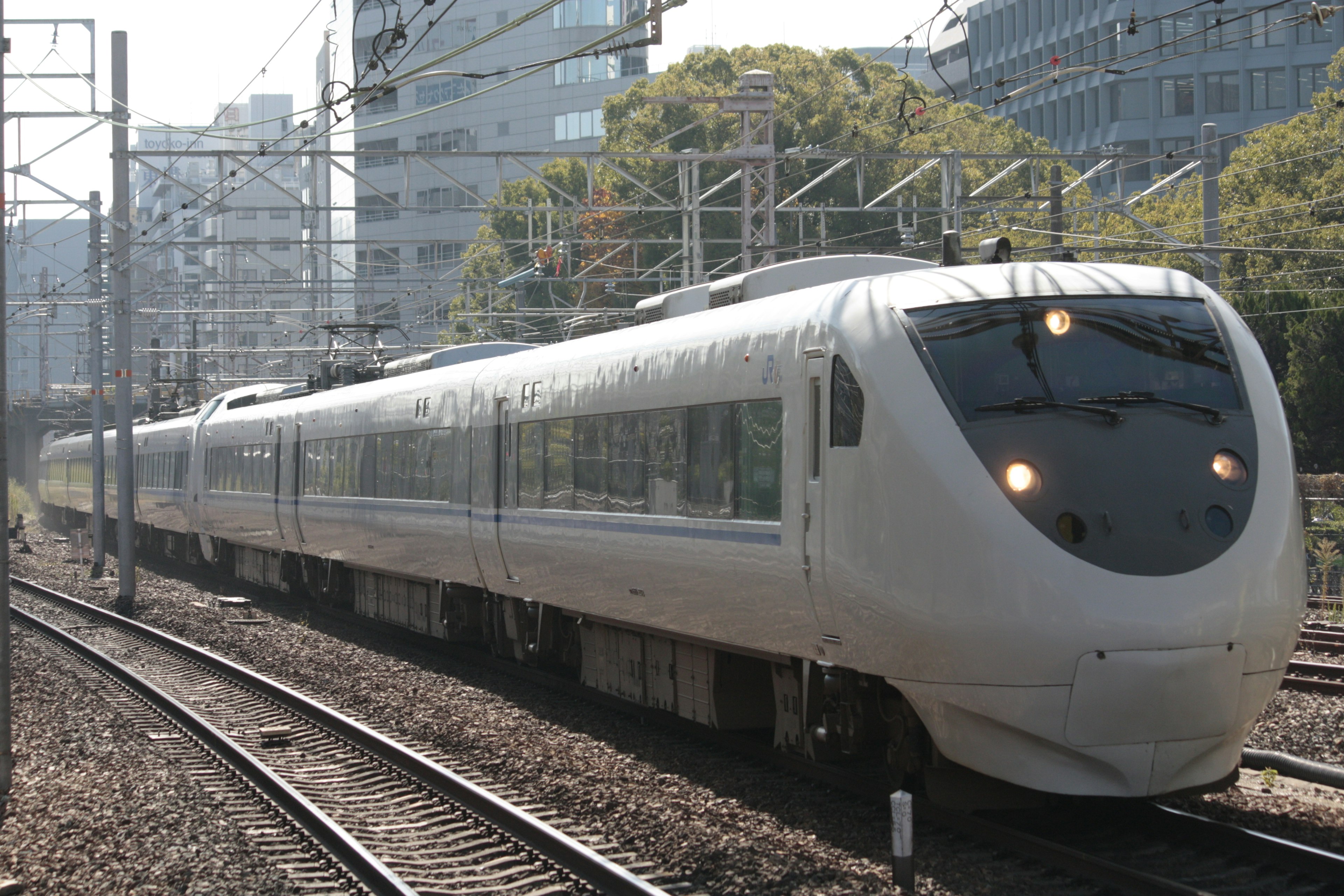 Un tren blanco que circula por las vías en un entorno urbano