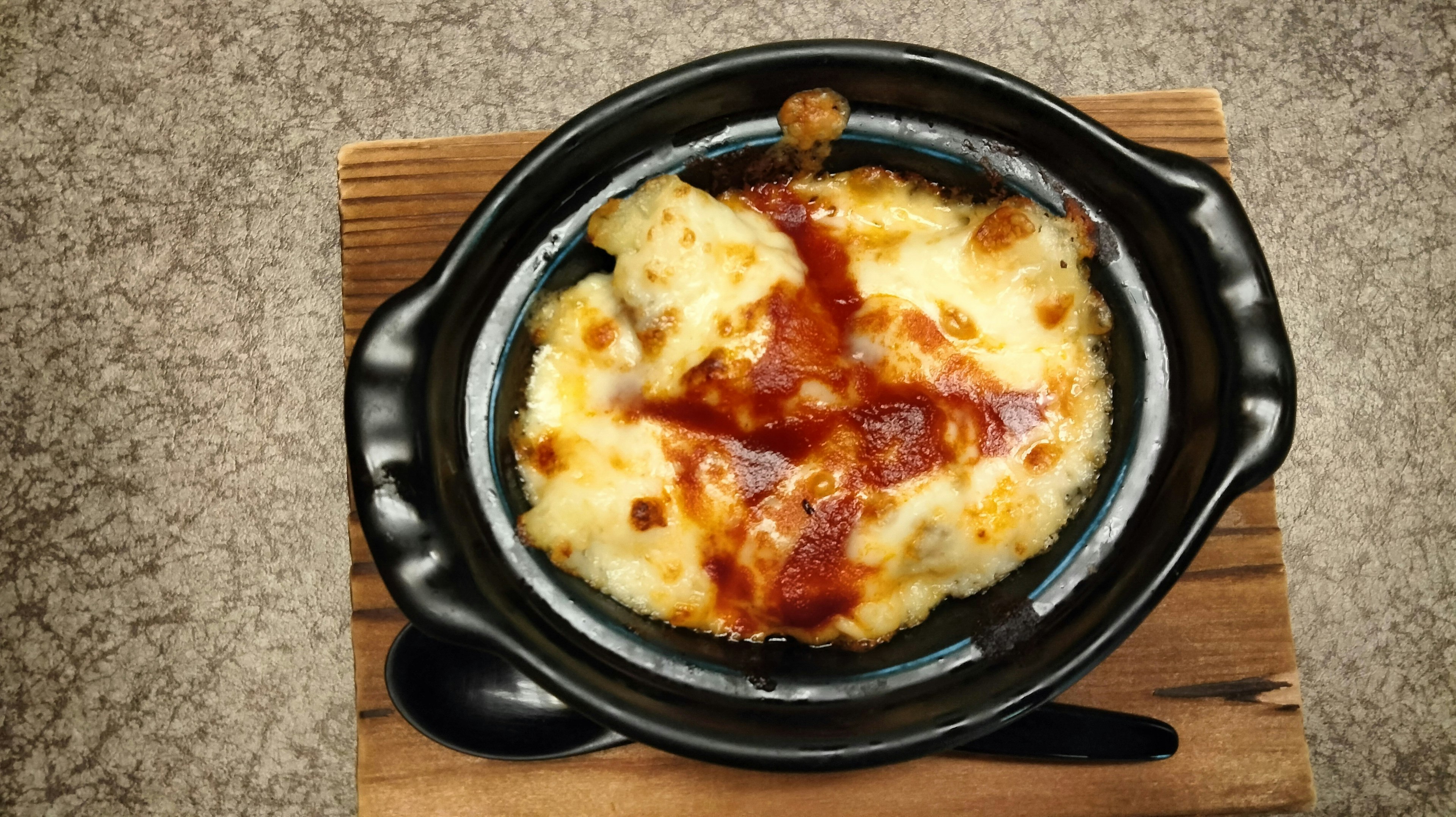 Piatto caldo con formaggio e salsa di pomodoro in una ciotola di ceramica nera