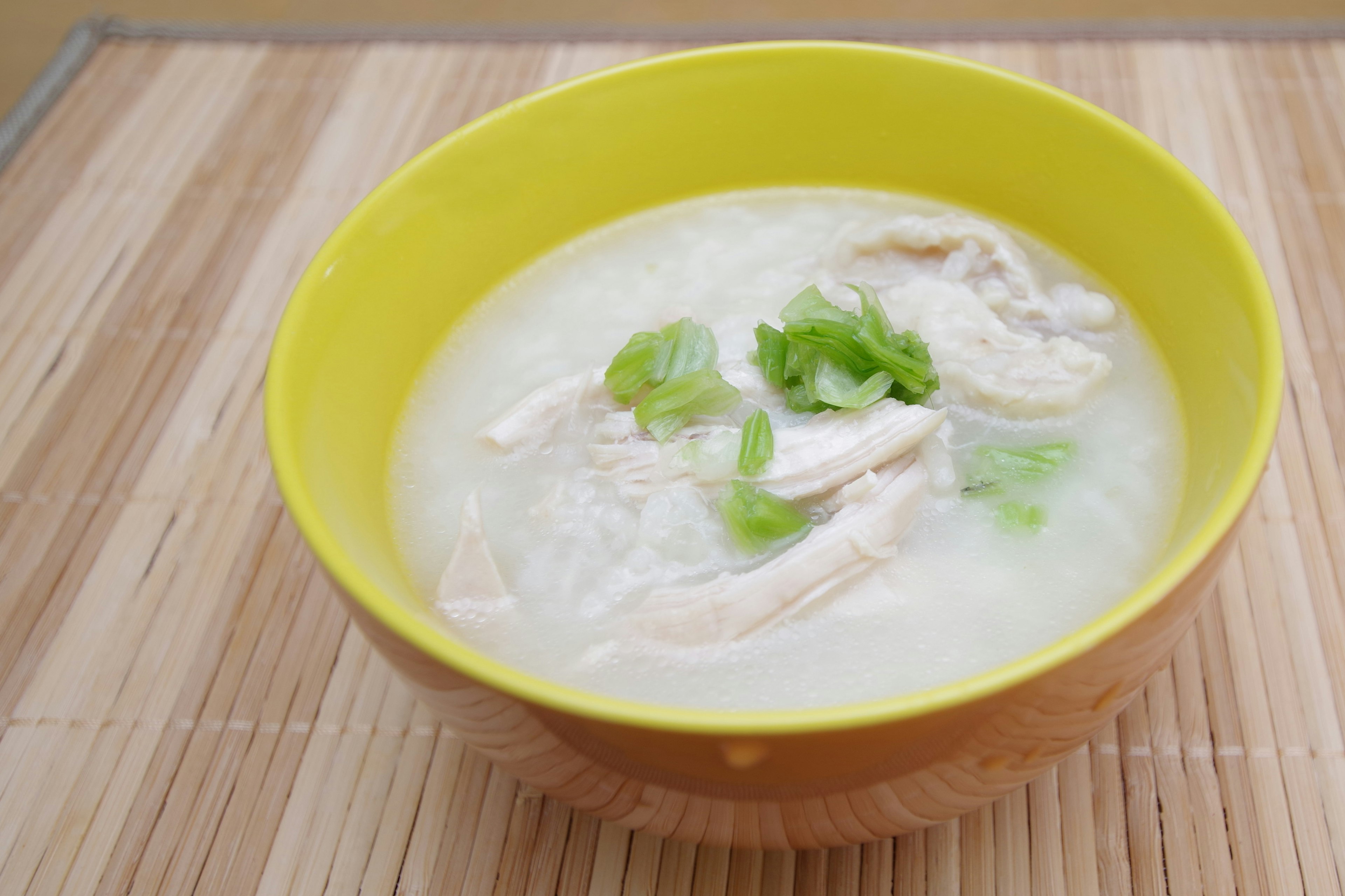 Cremige Hühnersuppe mit Frühlingszwiebeln in einer gelben Schüssel