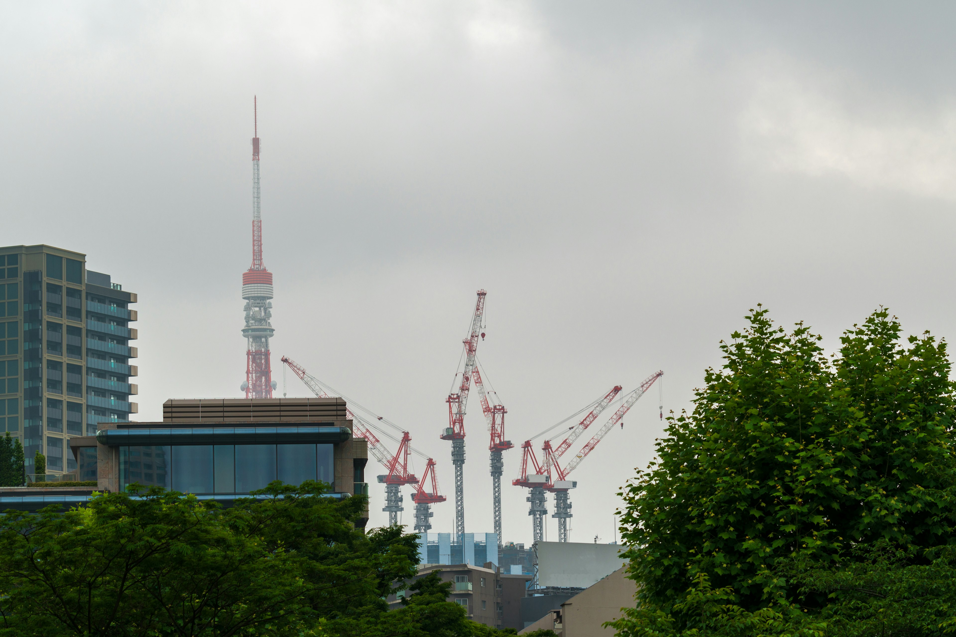 View of Tokyo Tower with construction cranes on a cloudy day