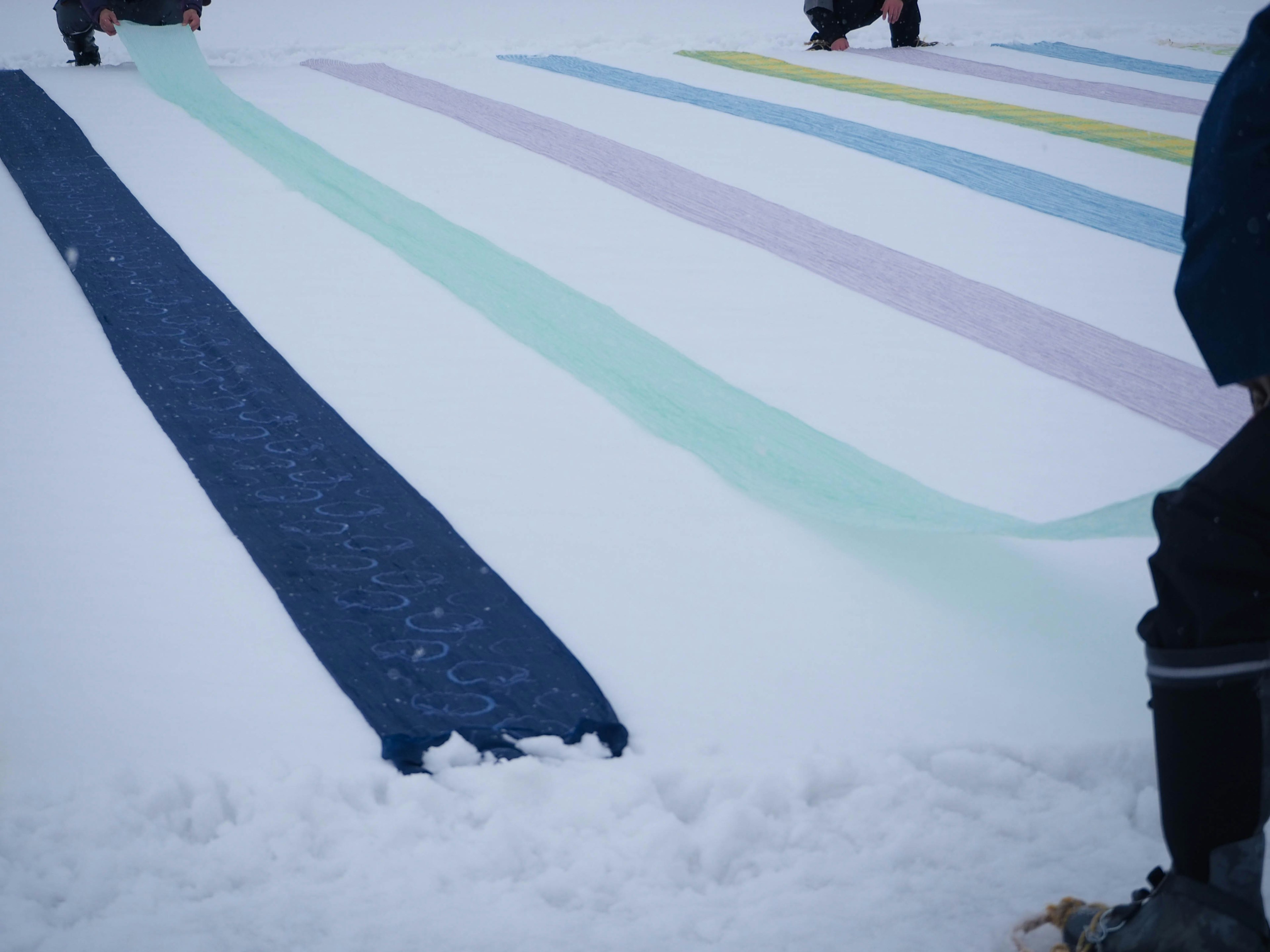 雪の上に色とりどりのストライプの布が広がっている