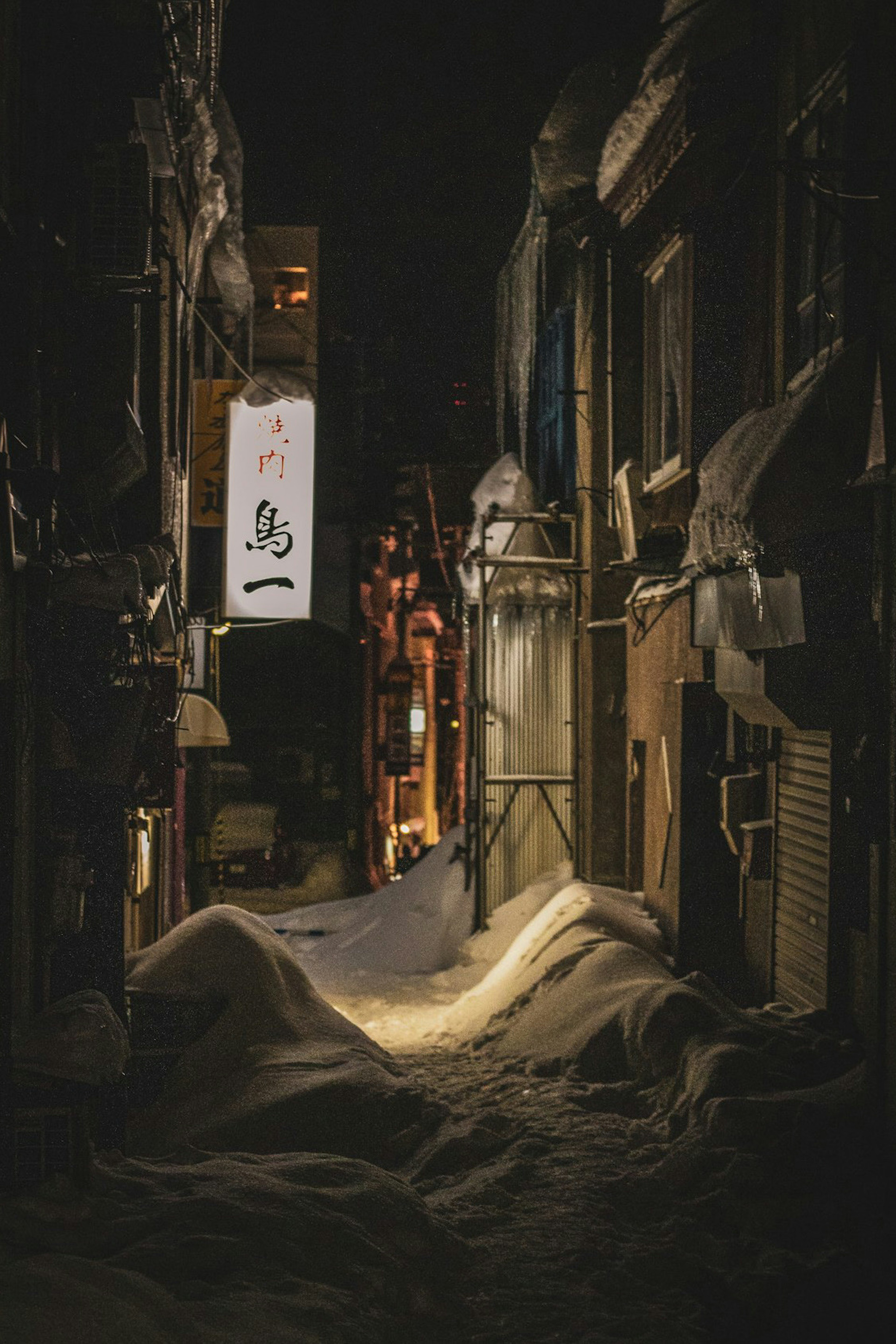 Schneebedeckte Gasse bei Nacht mit sichtbarem Schild