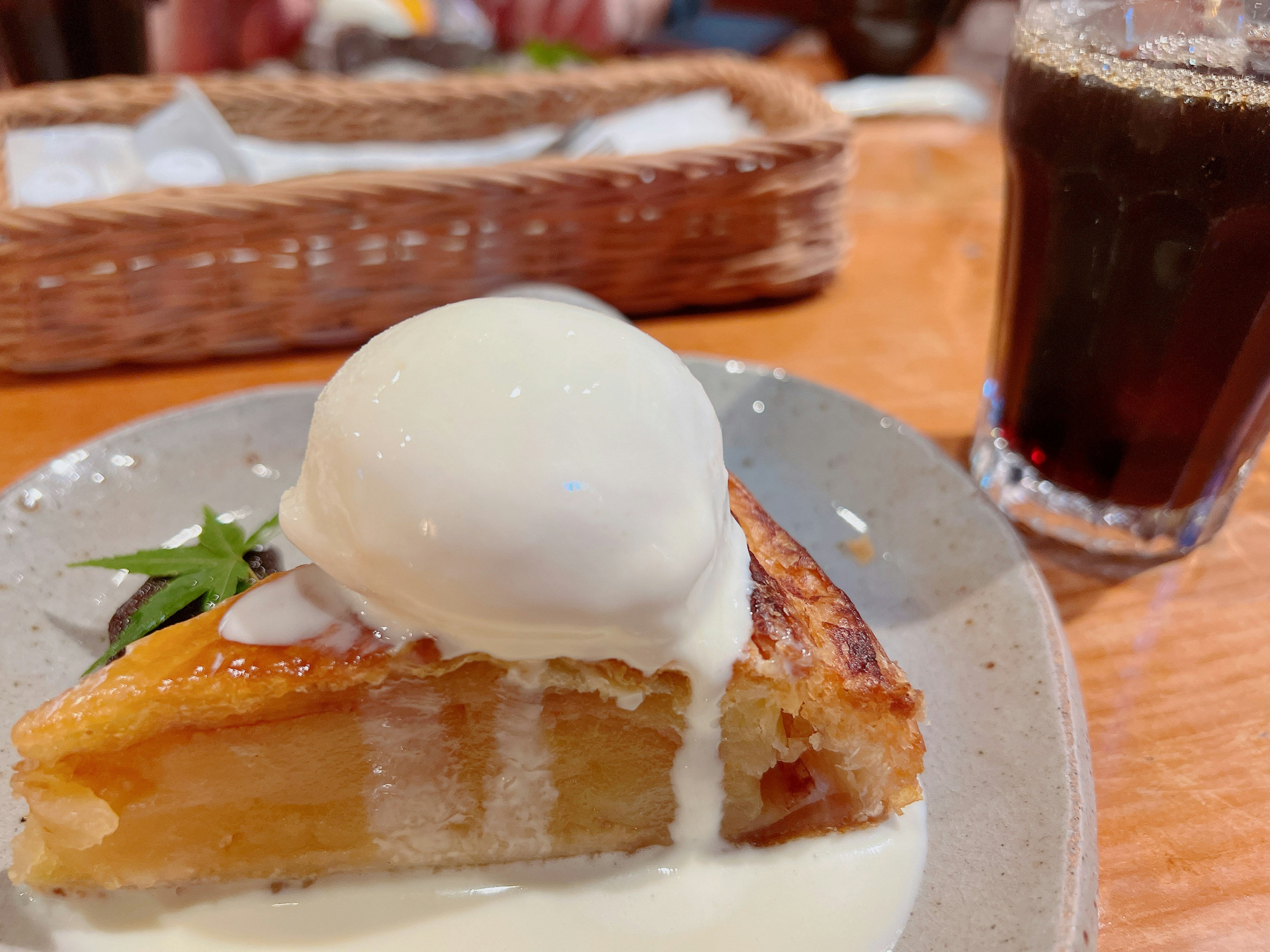 Fetta di torta di mele guarnita con crema e gelato accanto a una bevanda