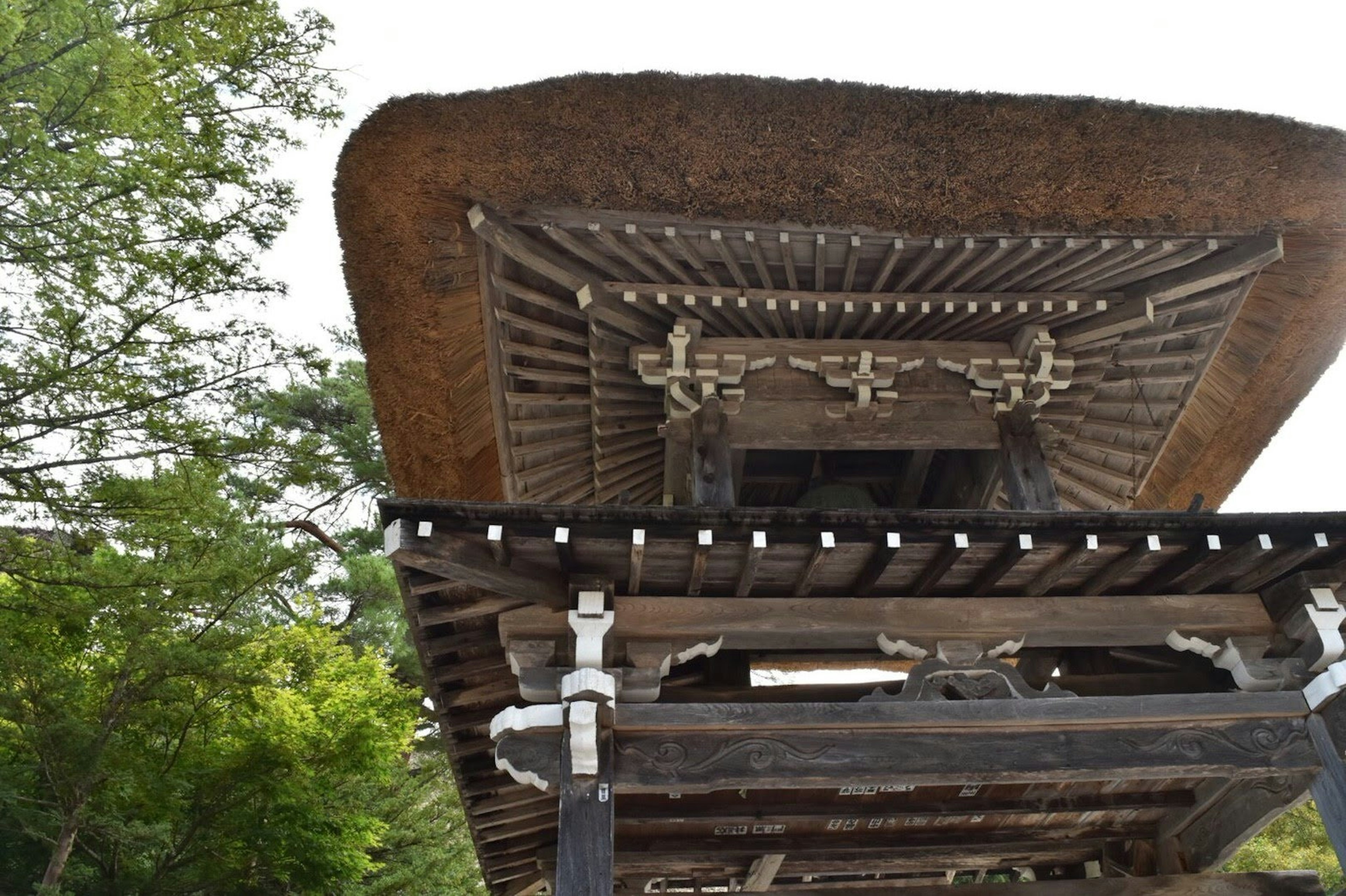 Vue d'une ancienne structure en bois avec un toit de chaume et des piliers de soutien